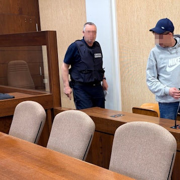 Der Angeklagte wurde von einem Wachtmeister in den Gerichtssaal geführt.