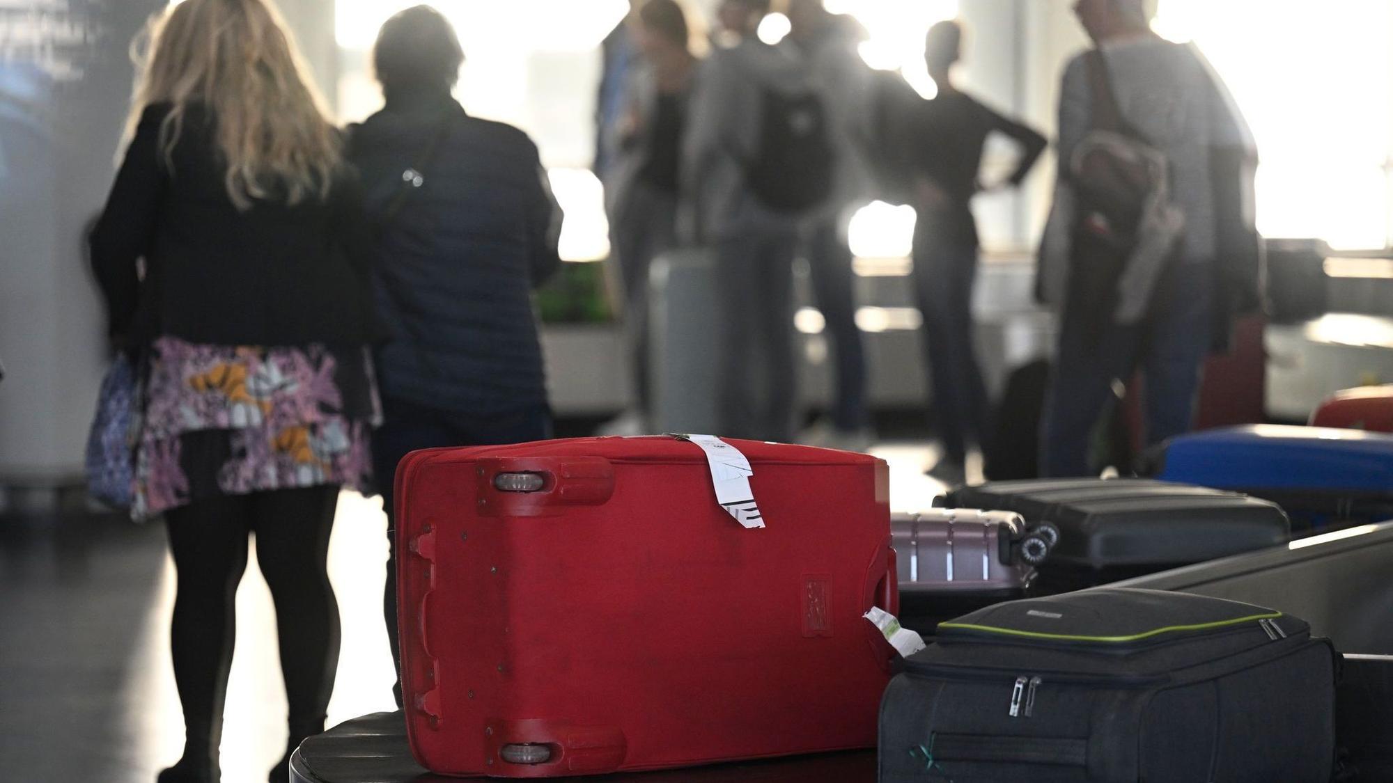 Passagiere warten am Gepäckband auf ihre Koffer