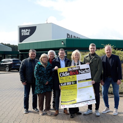 Fünf Männer und zwei Frauen stehen vor der Papstar-Zentrale in Kall und halten ein Plakat der Oldie-Nacht in die Kamera.