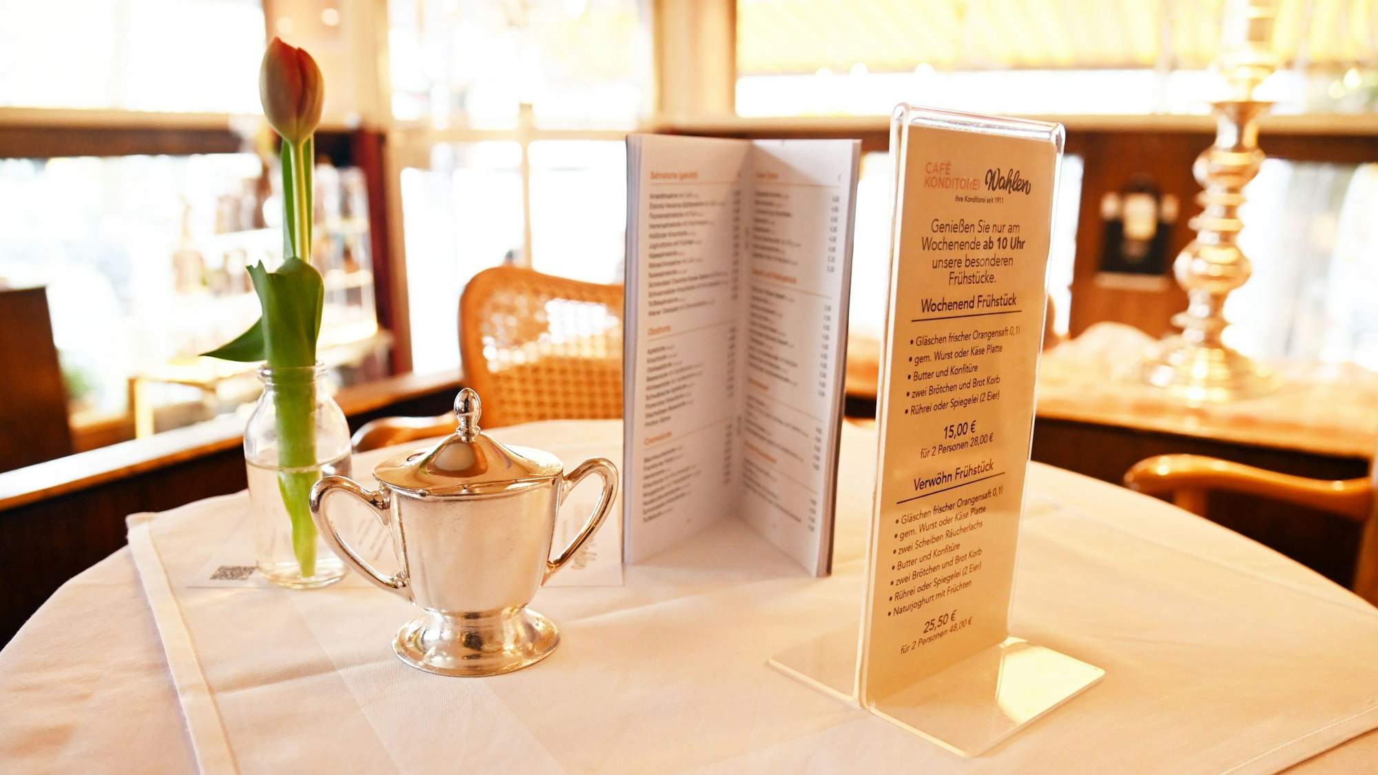 Runder Tisch mit Zuckerdose in Silber, Tulpe und Speisekarten.