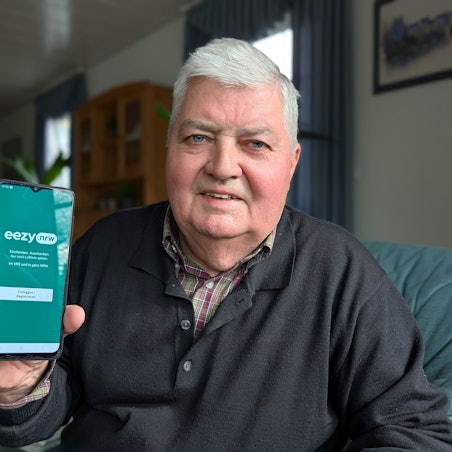 Das Foto zeigt Gerd Fabian mit der geöffneten App auf seinem Smartphone.