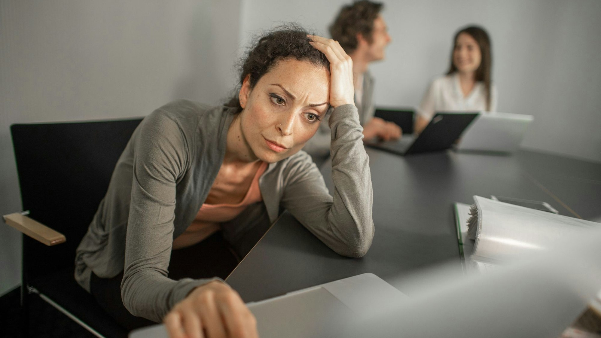 Frau sitzt grübelnd vor ihrem Laptop im Büro