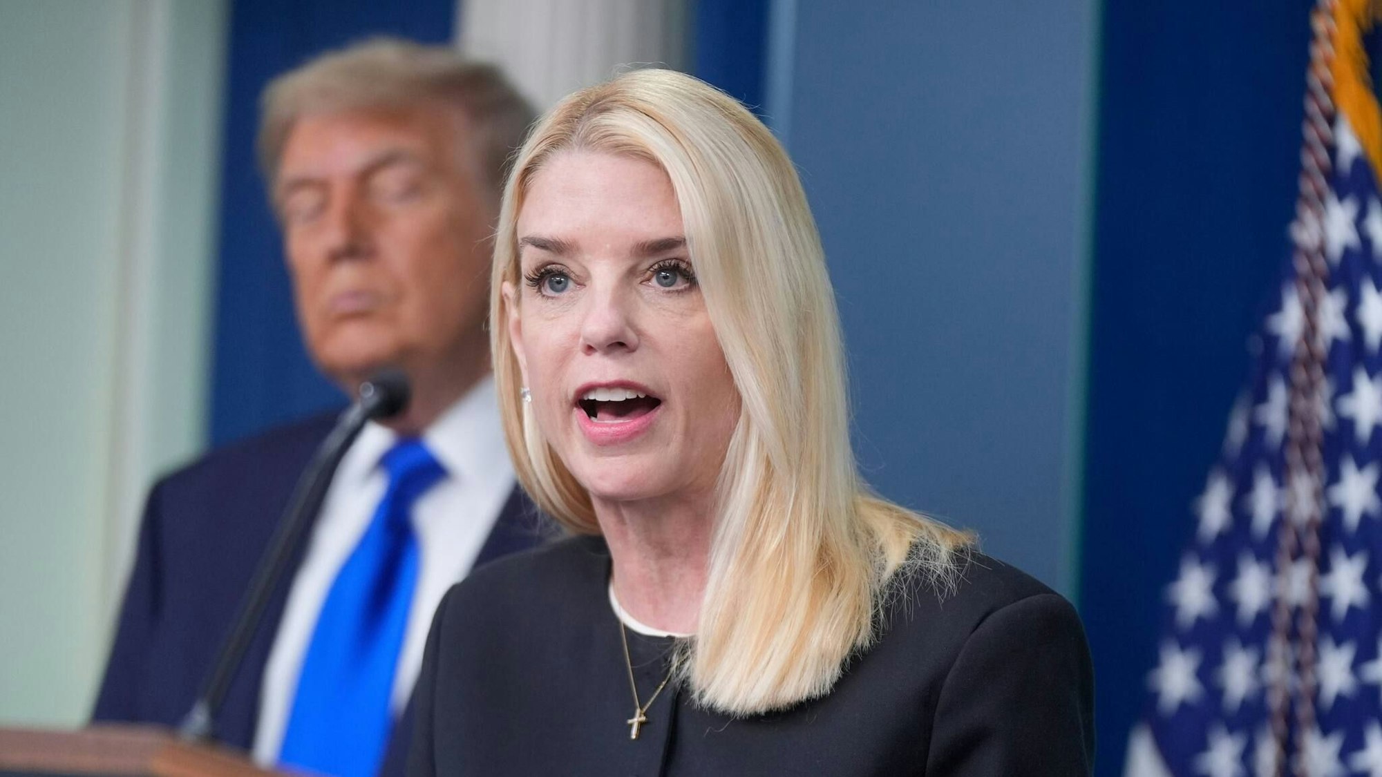 Justizministerin Pam Bondi spricht im Weißen Haus, im Hintergrund hört US-Präsident Donald Trump zu.
