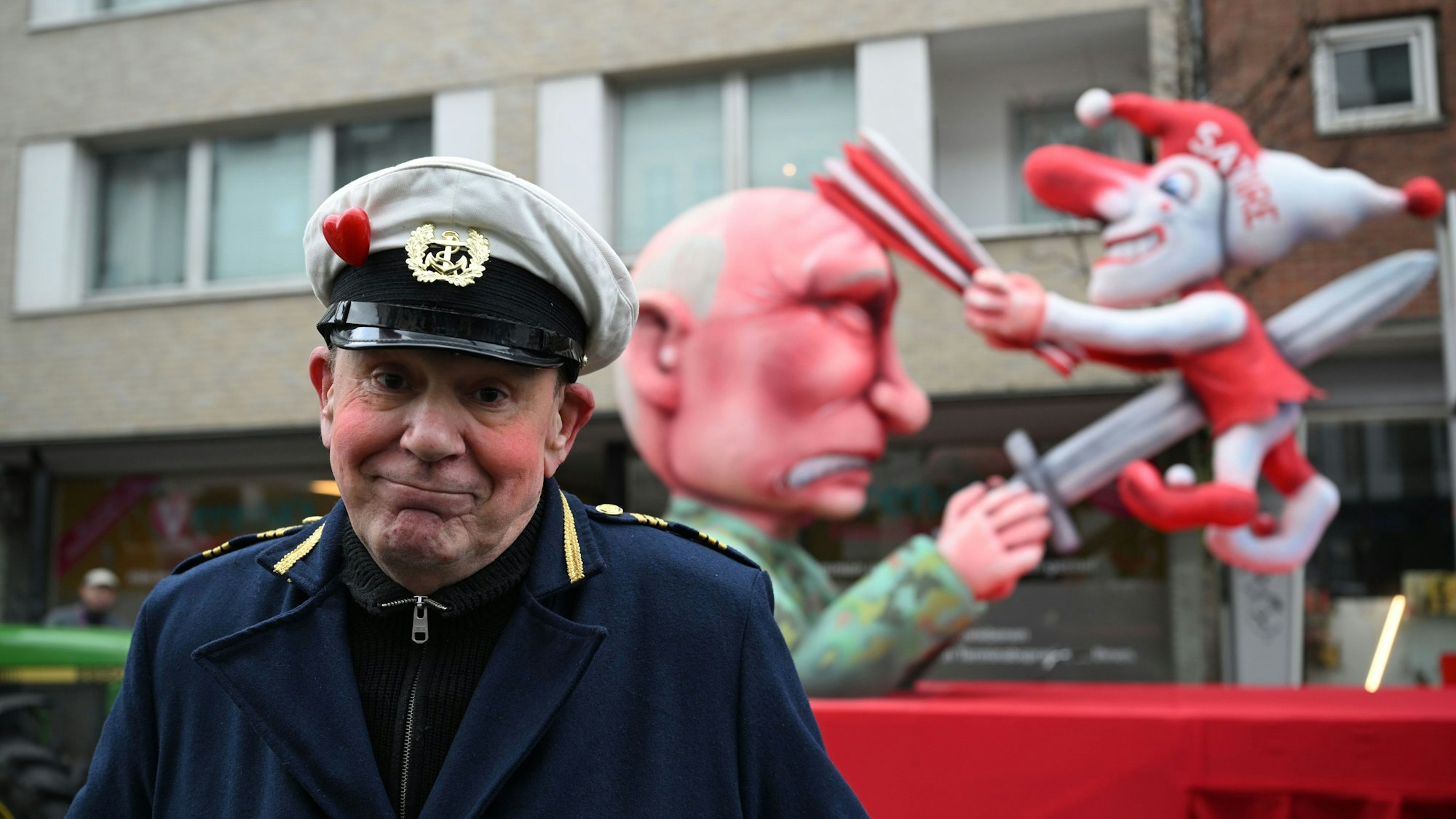 Jacques Tilly vor dem Mottowagen, auf dem Putin die Düsseldorfer Karnevalsfigur Hoppeditz aufspießt.