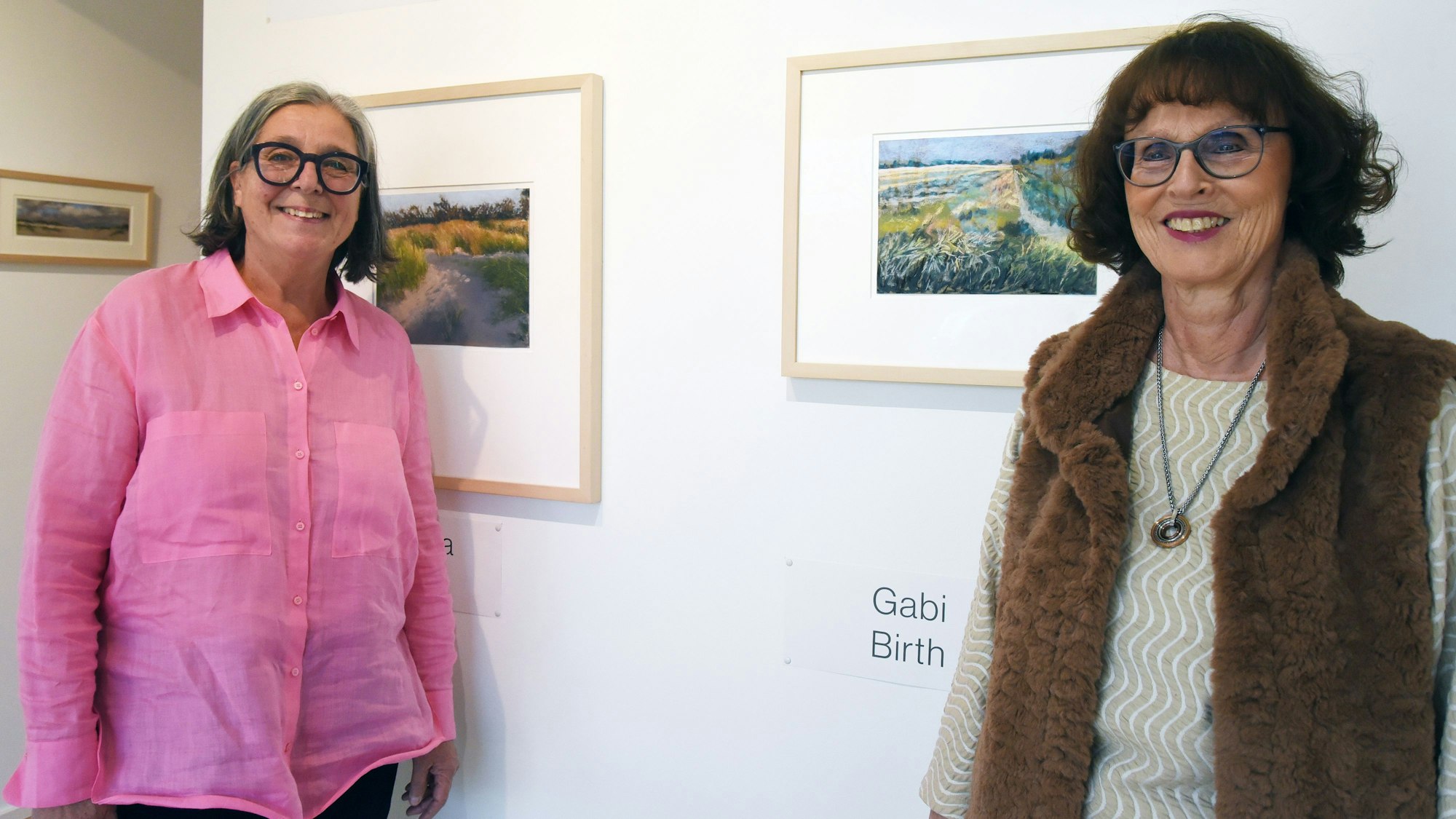 Zwei Frauen vor Bildern an der Wand.