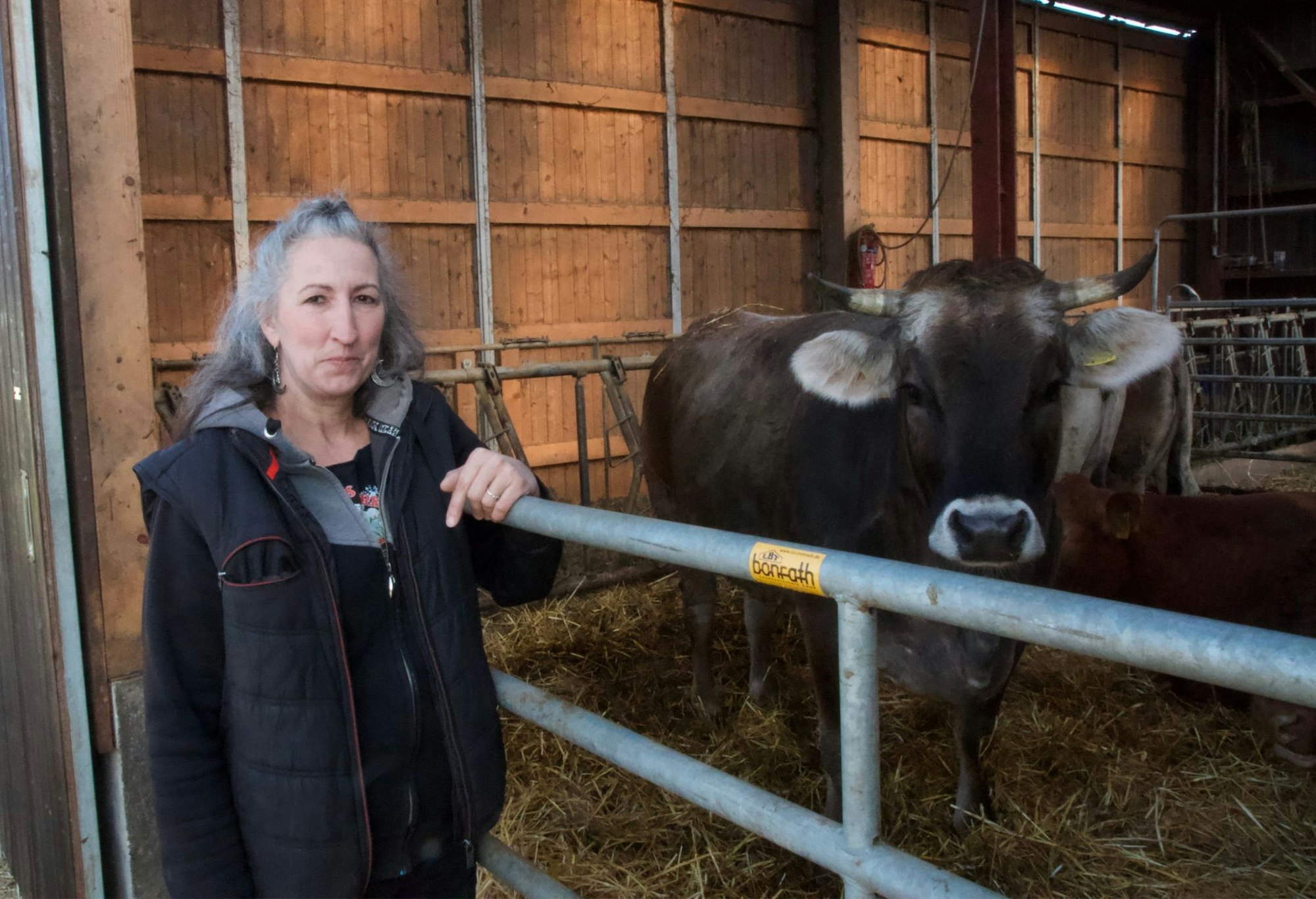 Eine Frau steht neben einer braunen Kuh, beide schauen in die Kamera