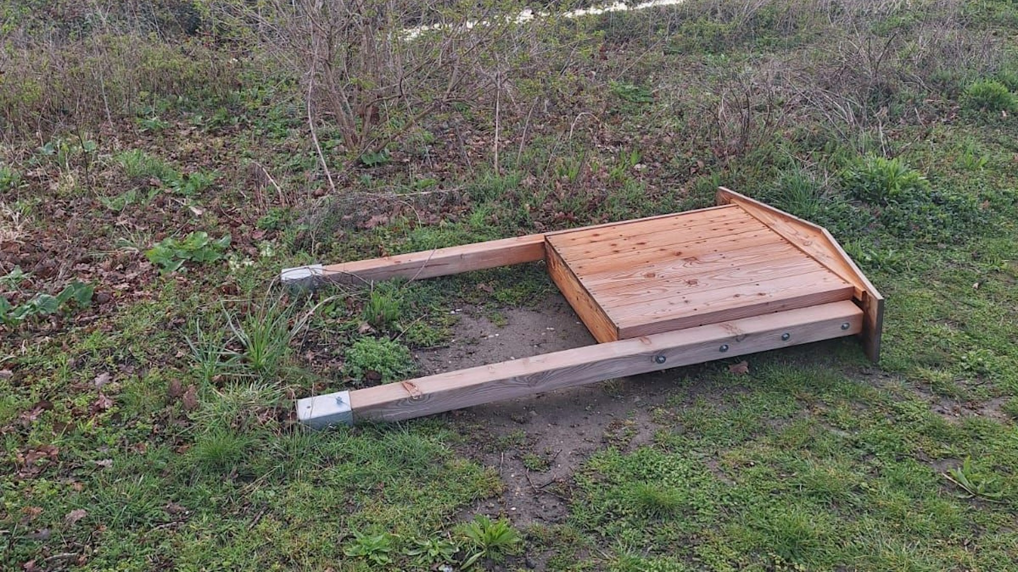 Ein Wildbienenhotel liegt auf einer Wiese.