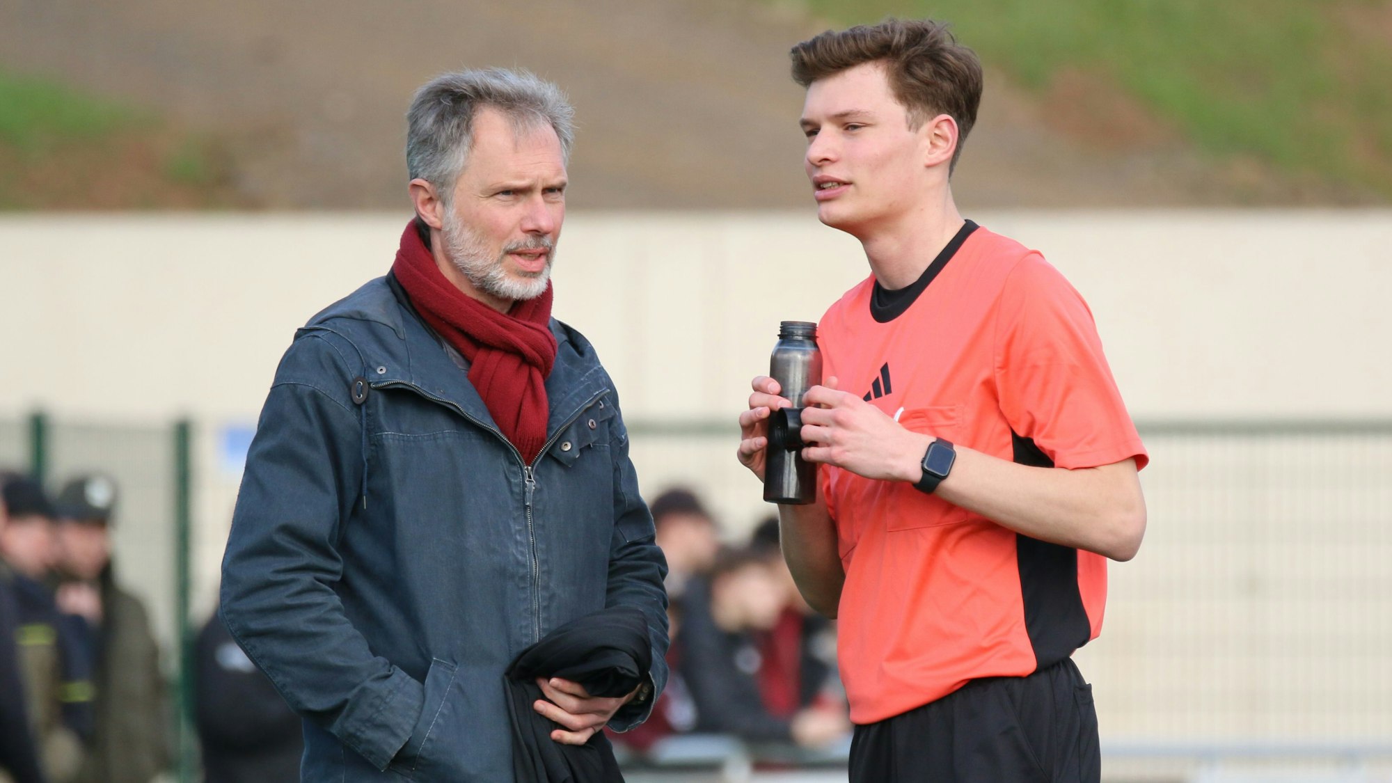 Arne Lichtenhagen hält eine Trinkflasche in der Hand und spricht mit seinem Vater.