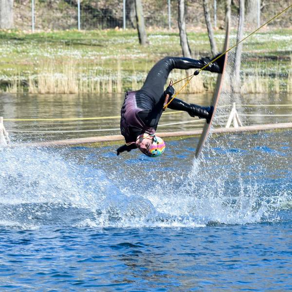 Das Foto zeigt einen Sportler, der Wakeboard fährt.