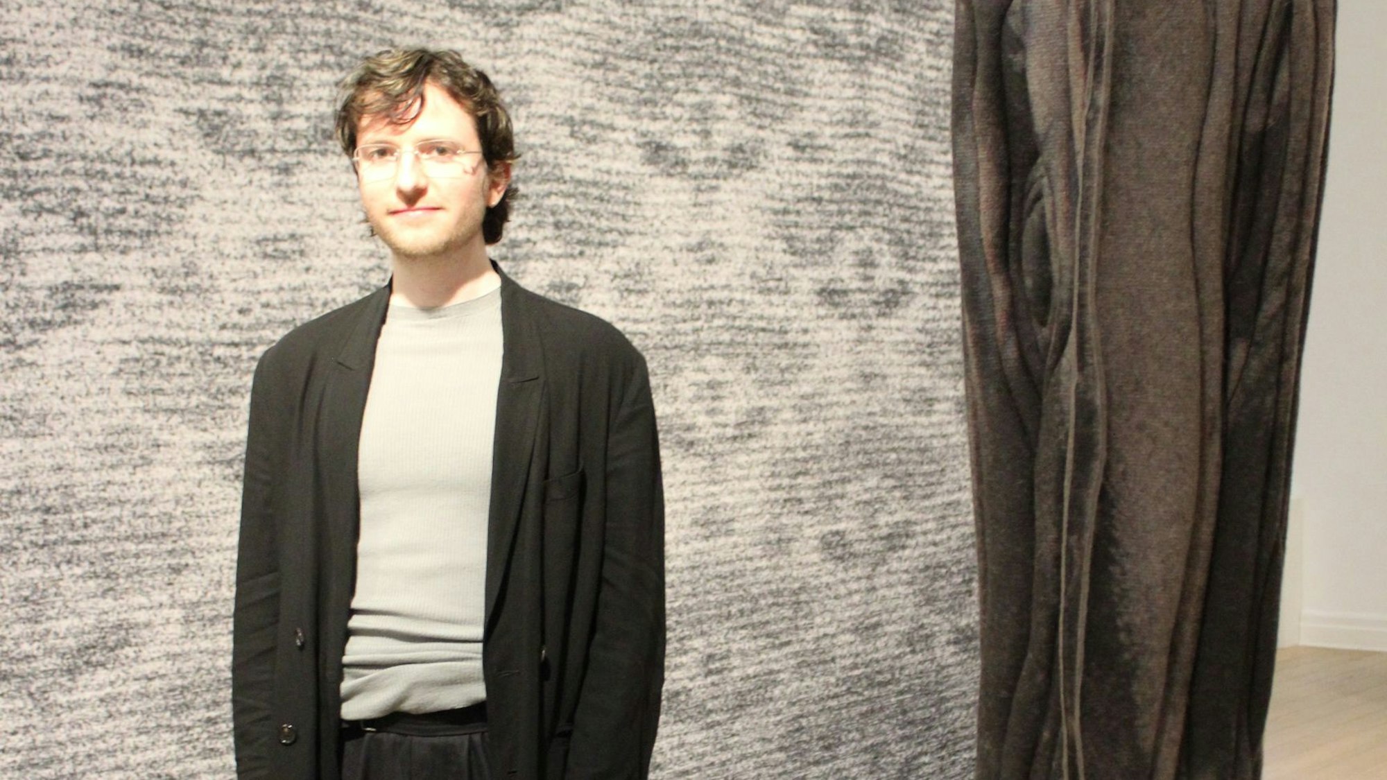 Ein Mann steht vor einem Wandteppich.