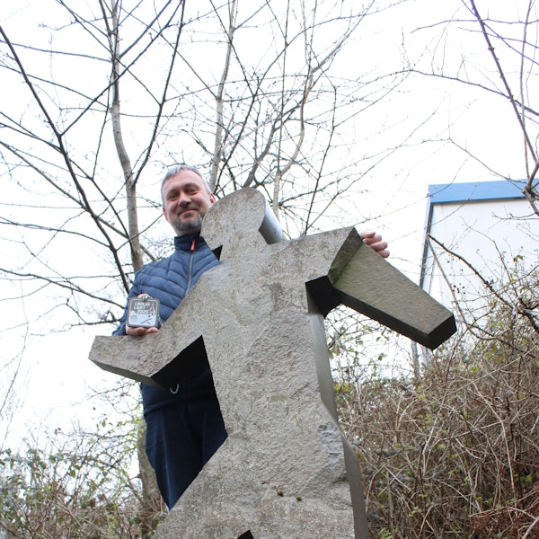 Ein Mann steht hinter einer Figur aus Grauwacke.