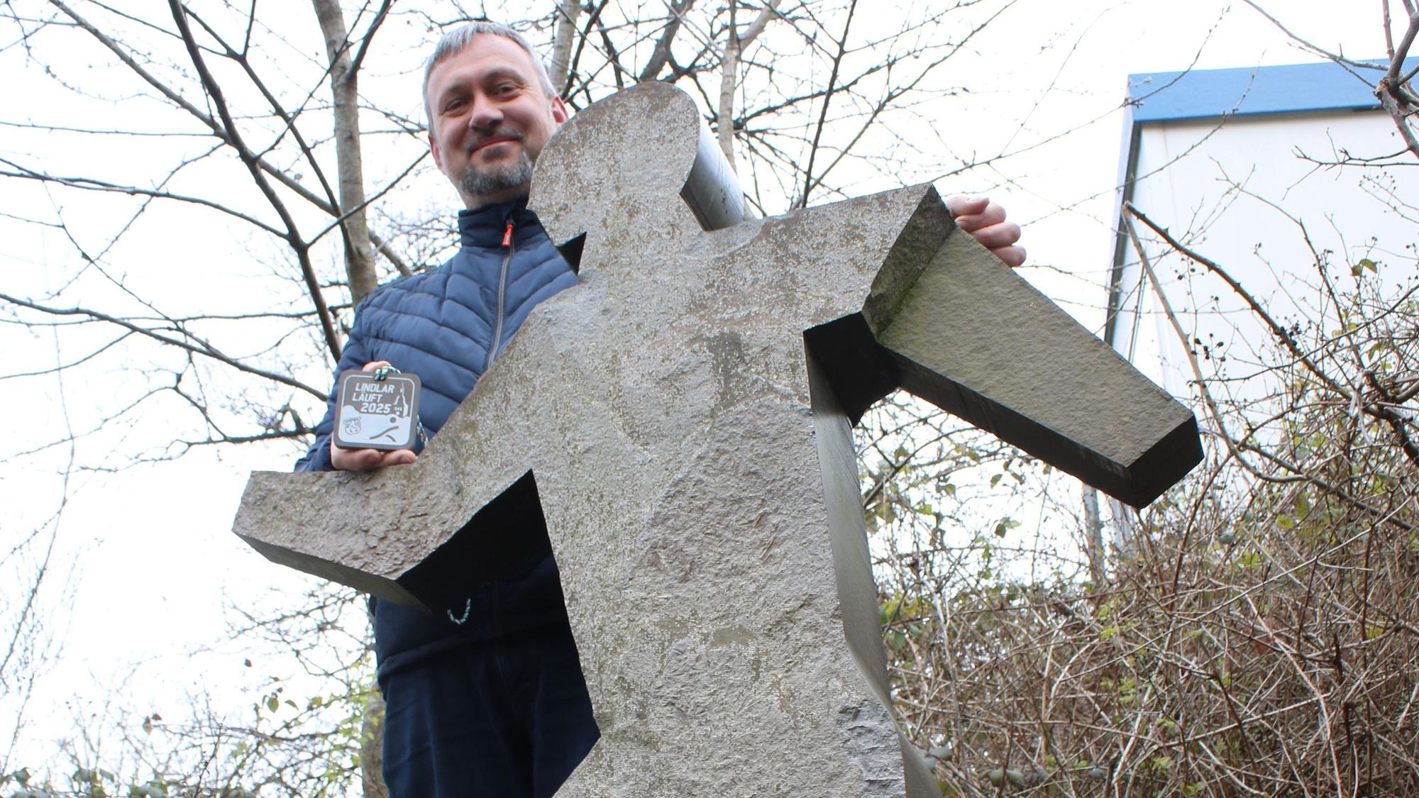 Ein Mann steht hinter einer Figur aus Grauwacke.