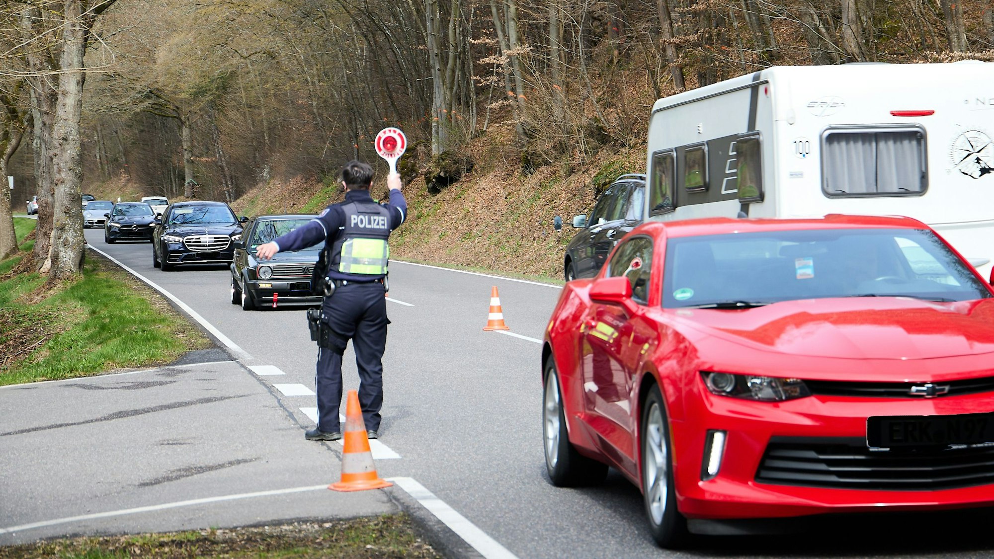 Ein Polizeibeamter winkt mit einer Kelle Autos auf einen Parkplatz.