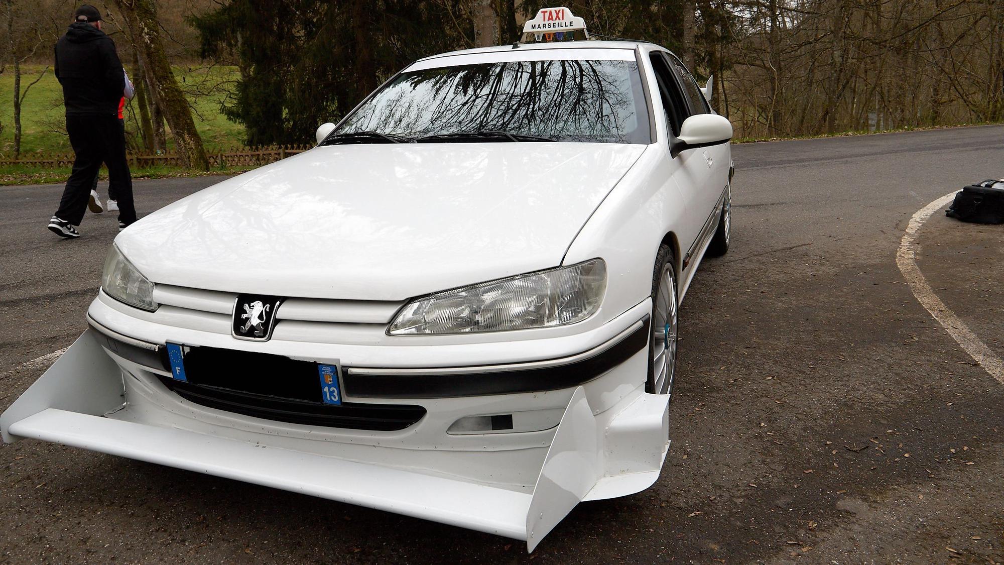 Ein weißer Peugeot 406 mit Taxi-Schild und einem großen, scharfkantigem Frontspoiler.