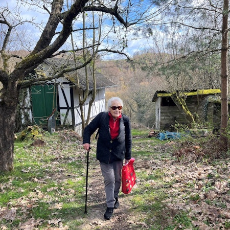 Die alte Dame stützt sich auf einen Stock.