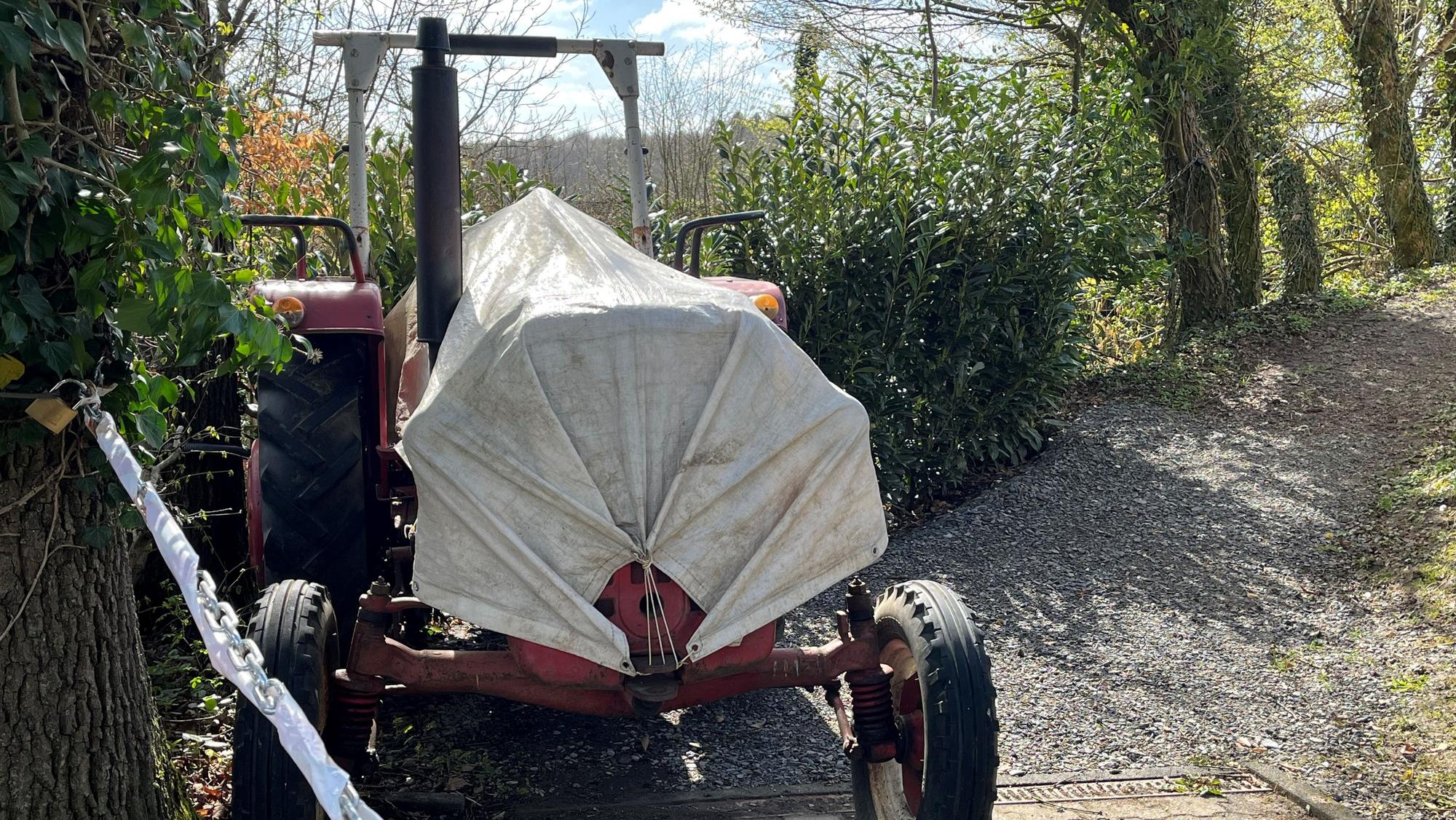 Im Vordergrund sind eine Kette und ein Traktor zu sehen, im Hintergrund die Bäume.