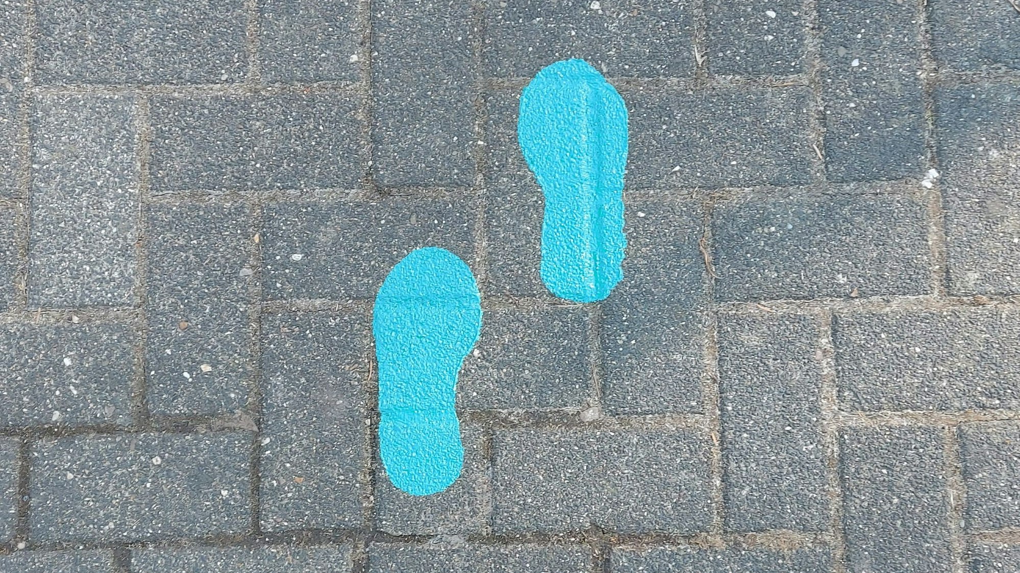 Auf Pflaster sind blaue Fußspuren angebracht.