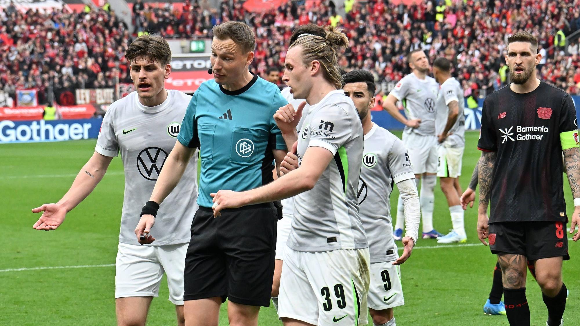 GER, 1.FBL. Bayer 04 Leverkusen vs. VfL Wolfsburg / 04.04.2026, BayArena, Leverkusen, GER, 1.FBL. Bayer 04 Leverkusen vs. VfL Wolfsburg, im Bild: im Vorweg zum 11 Meter für Leverkusen gab es Diskussionen um das Foul im Strafraum Martin Petersen Schiedsrichter / referee Patrick Wimmer VfL Wolfsburg 39, Mohamed Amoura VfL Wolfsburg 9, Robert Andrich Leverkusen 8, *** GER, 1 FBL Bayer 04 Leverkusen vs VfL Wolfsburg 04 04 2026, BayArena, Leverkusen, GER, 1 FBL Bayer 04 Leverkusen vs VfL Wolfsburg, in the picture before the 11 meters for Leverkusen there were discussions about the foul in the penalty area Martin Petersen Referee referee Patrick Wimmer VfL Wolfsburg 39 , Mohamed Amoura VfL Wolfsburg 9 , Robert Andrich Leverkusen 8 , nordphotoxGmbHx/xMeuter nph00351