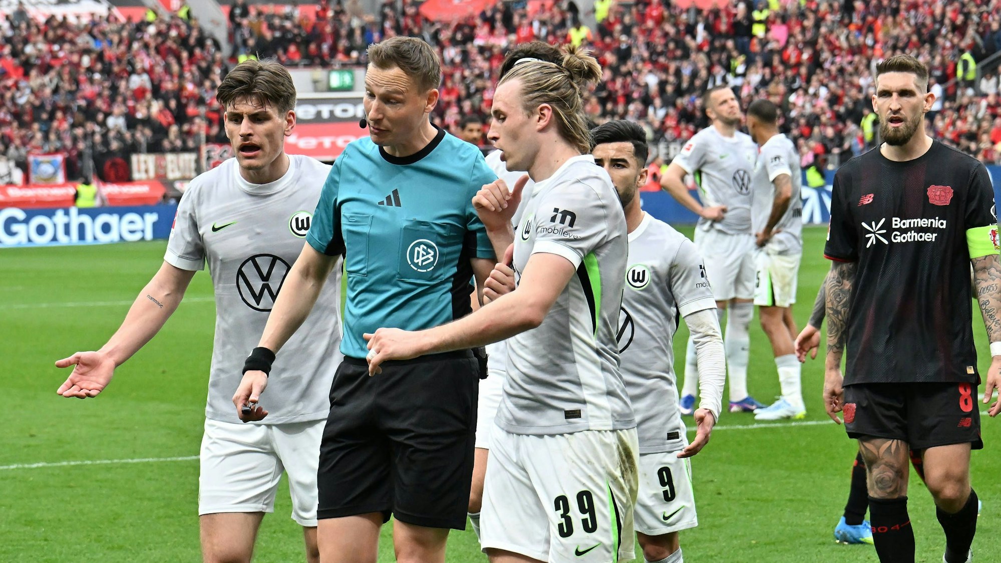 GER, 1.FBL. Bayer 04 Leverkusen vs. VfL Wolfsburg / 04.04.2026, BayArena, Leverkusen, GER, 1.FBL. Bayer 04 Leverkusen vs. VfL Wolfsburg, im Bild: im Vorweg zum 11 Meter für Leverkusen gab es Diskussionen um das Foul im Strafraum Martin Petersen Schiedsrichter / referee Patrick Wimmer VfL Wolfsburg 39, Mohamed Amoura VfL Wolfsburg 9, Robert Andrich Leverkusen 8, *** GER, 1 FBL Bayer 04 Leverkusen vs VfL Wolfsburg 04 04 2026, BayArena, Leverkusen, GER, 1 FBL Bayer 04 Leverkusen vs VfL Wolfsburg, in the picture before the 11 meters for Leverkusen there were discussions about the foul in the penalty area Martin Petersen Referee referee Patrick Wimmer VfL Wolfsburg 39 , Mohamed Amoura VfL Wolfsburg 9 , Robert Andrich Leverkusen 8 , nordphotoxGmbHx/xMeuter nph00351