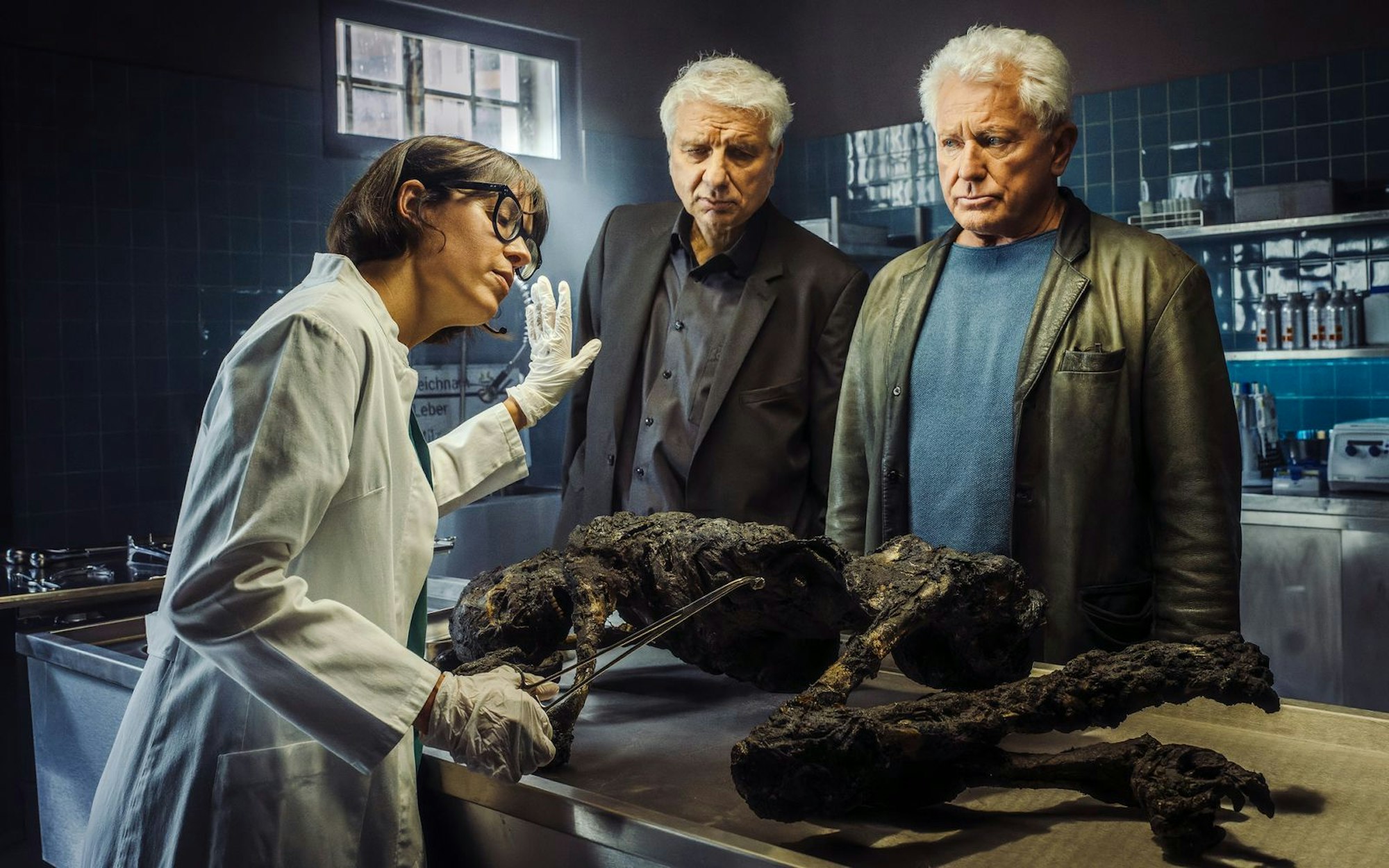 Die Kabarettistin Eva Karl Faltermeier schlüpfte zum „Tatort“-Abschied von Franz Leitmayr (Udo Wachtveitl, Mitte) und Ivo Batic (Miroslav Nemec) in die Gastrolle der Rechtsmedizinerin Dr. Roswitha Schwarz-Fischer. (Bild: BR/NEUESUPER GmbH/Hendrik Heiden)