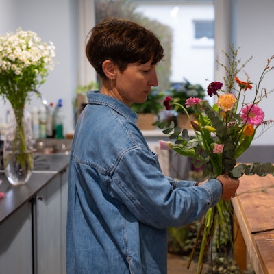 Eine Frau stellt einen Blumenstrauß zusammen.