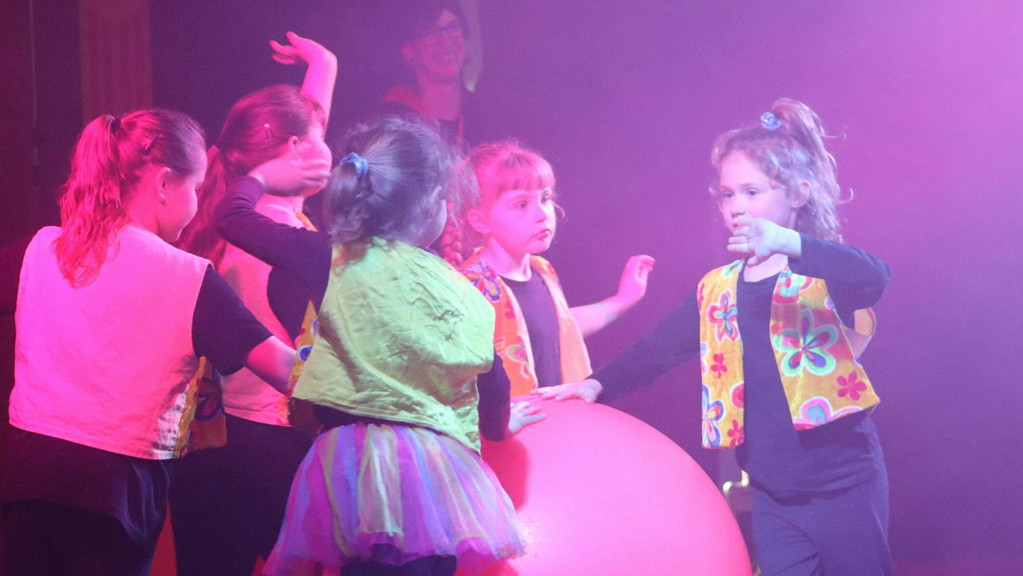 Kinder tanzen um einen Ball in der Manege.