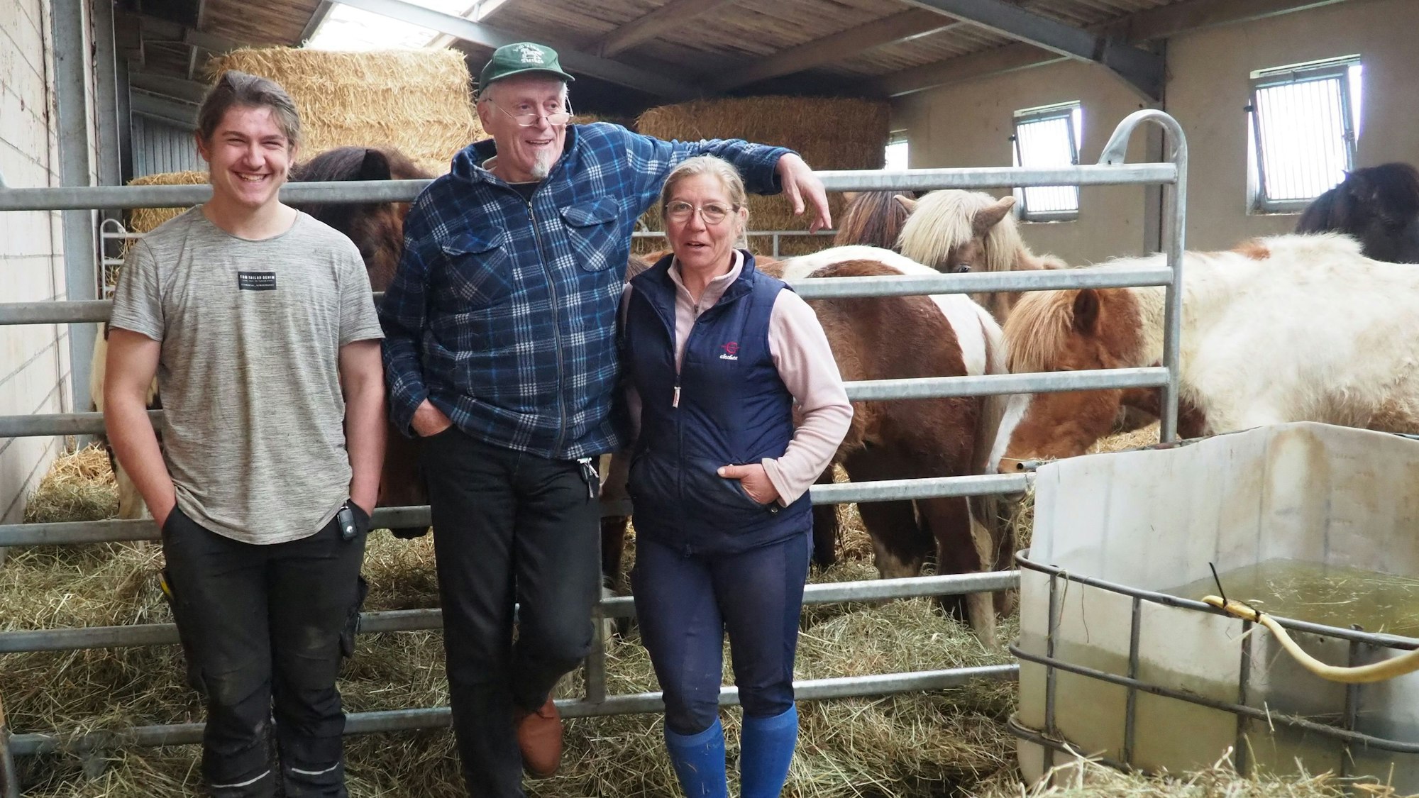 Felix und Dieter Pierkes und Heidi Schwohn stehen vor einer Gruppe Pferde.