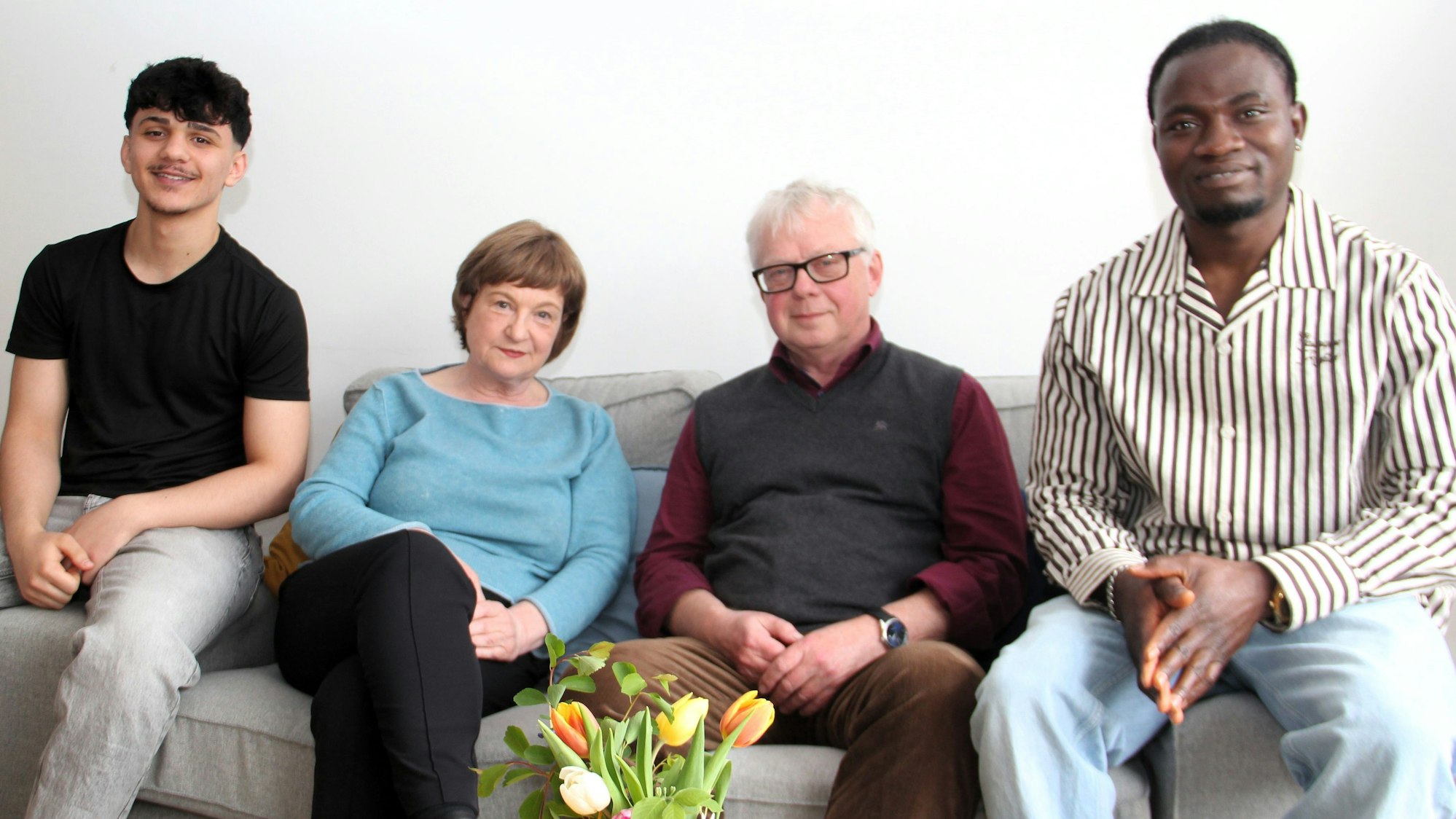 Vier Menschen sitzen auf einer Couch.