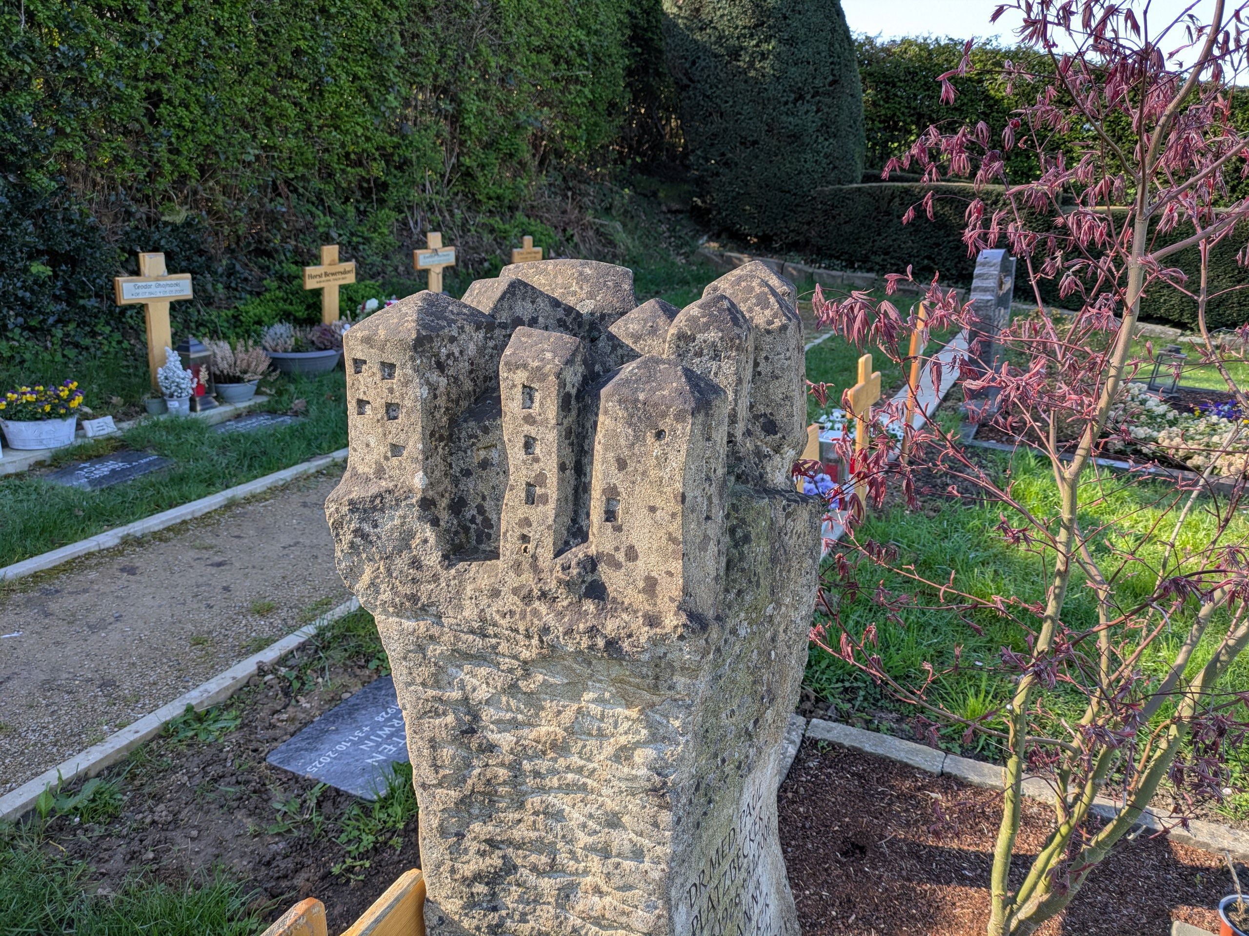 Ein Felsendorf ziert die Krone dieses Grabsteins auf dem Friedhof.