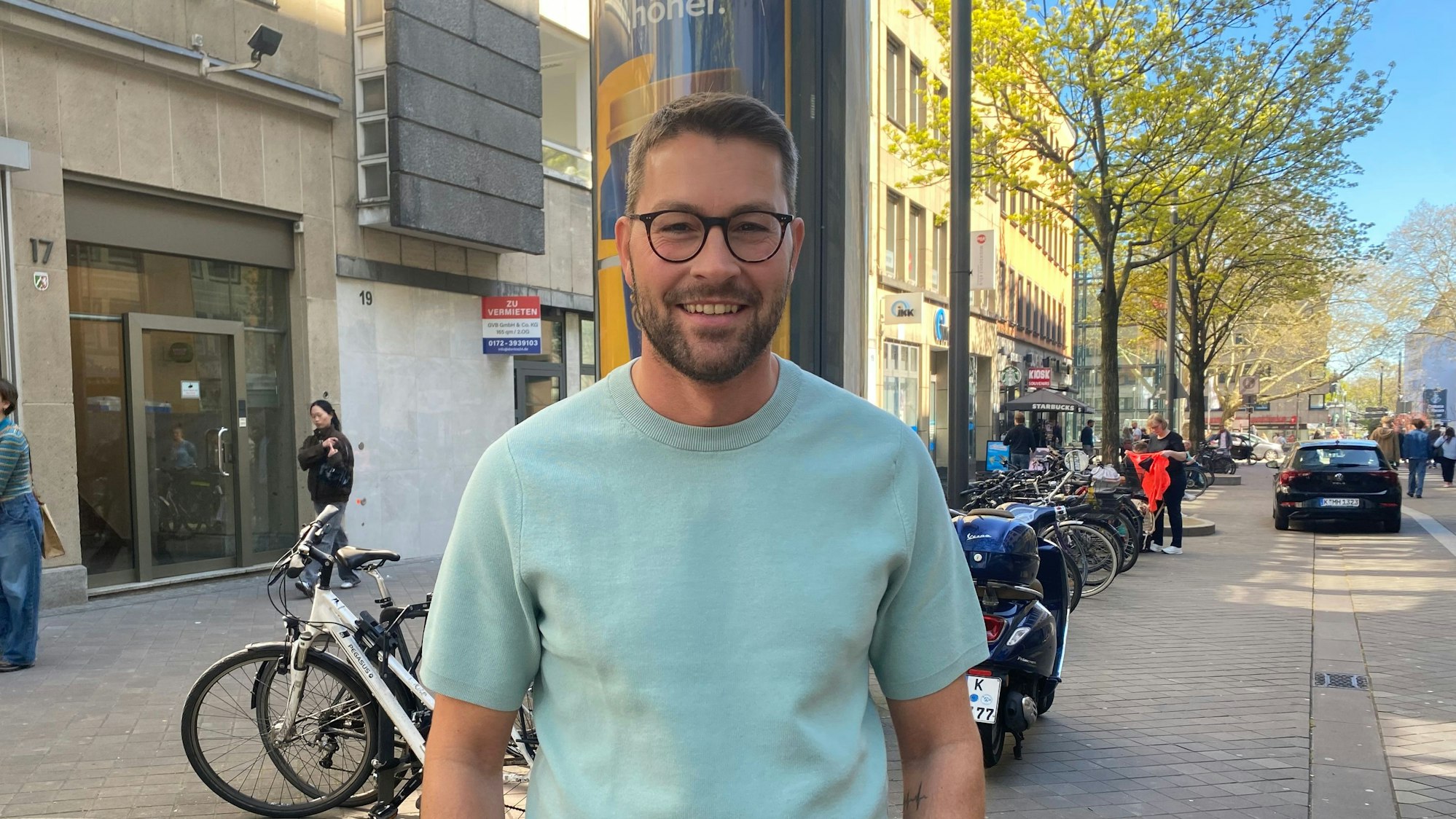 Ein Mann mit Brille und im blauen T-Shirt schaut in die Kamera.