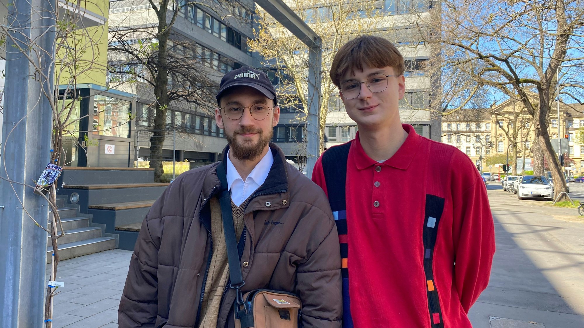 Zwei junge Männer, beide tragen eine Brille, schauen in die Kamera.