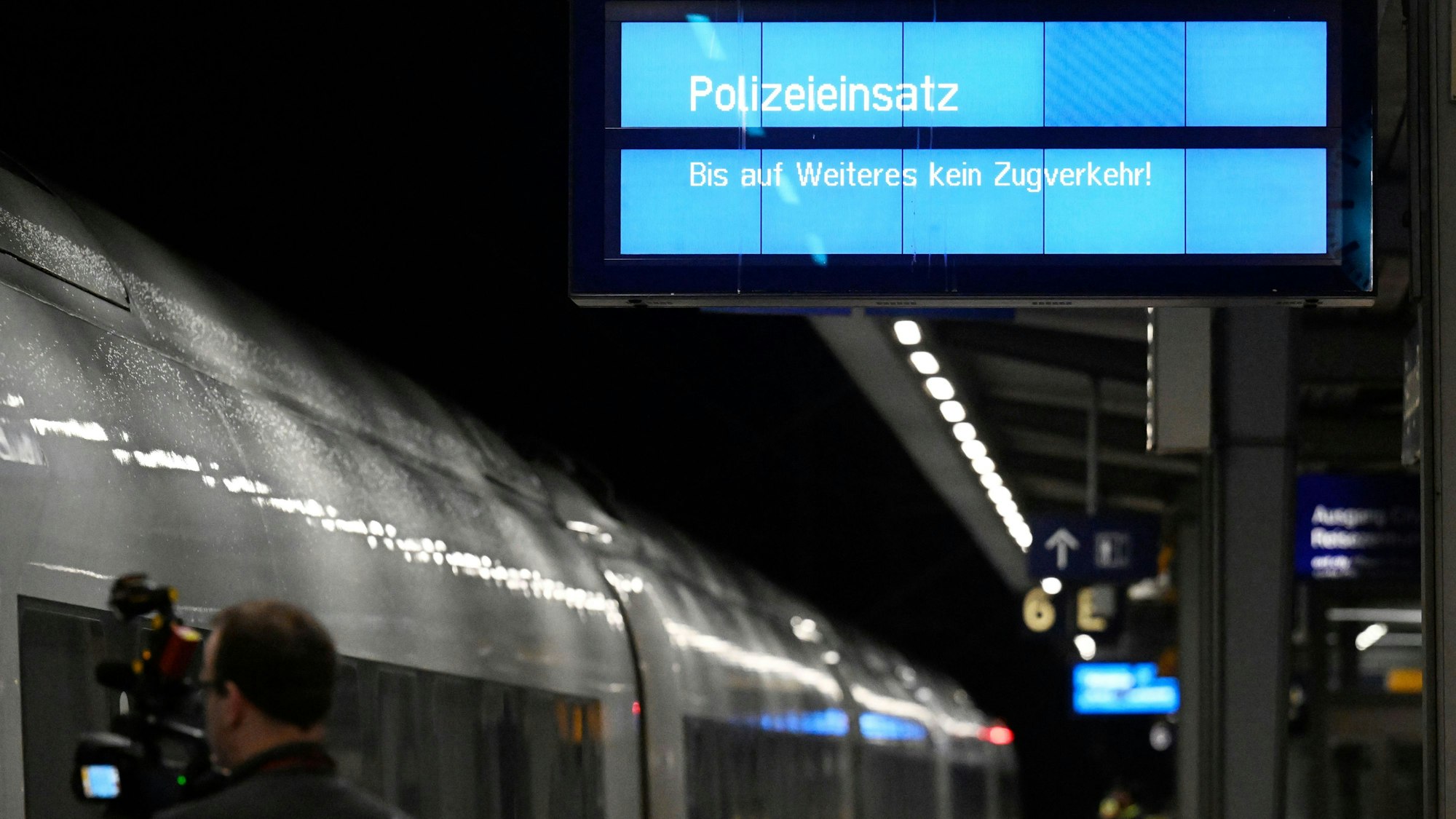 „Polizeieinsatz“ wird auf einem Display an einem Bahnsteig im Bahnhof Siegburg angezeigt, auf dem ein ICE der Deutschen Bahn steht. Ein Mann hatte mit einem Anschlag gedroht und mehrere Menschen leicht verletzt. (Archivbild)