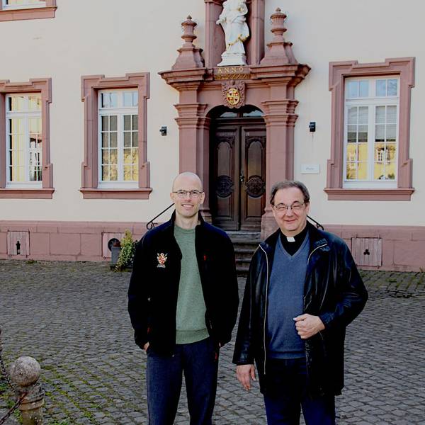 Zwei Männer stehen vor einem der Klostergebäude.