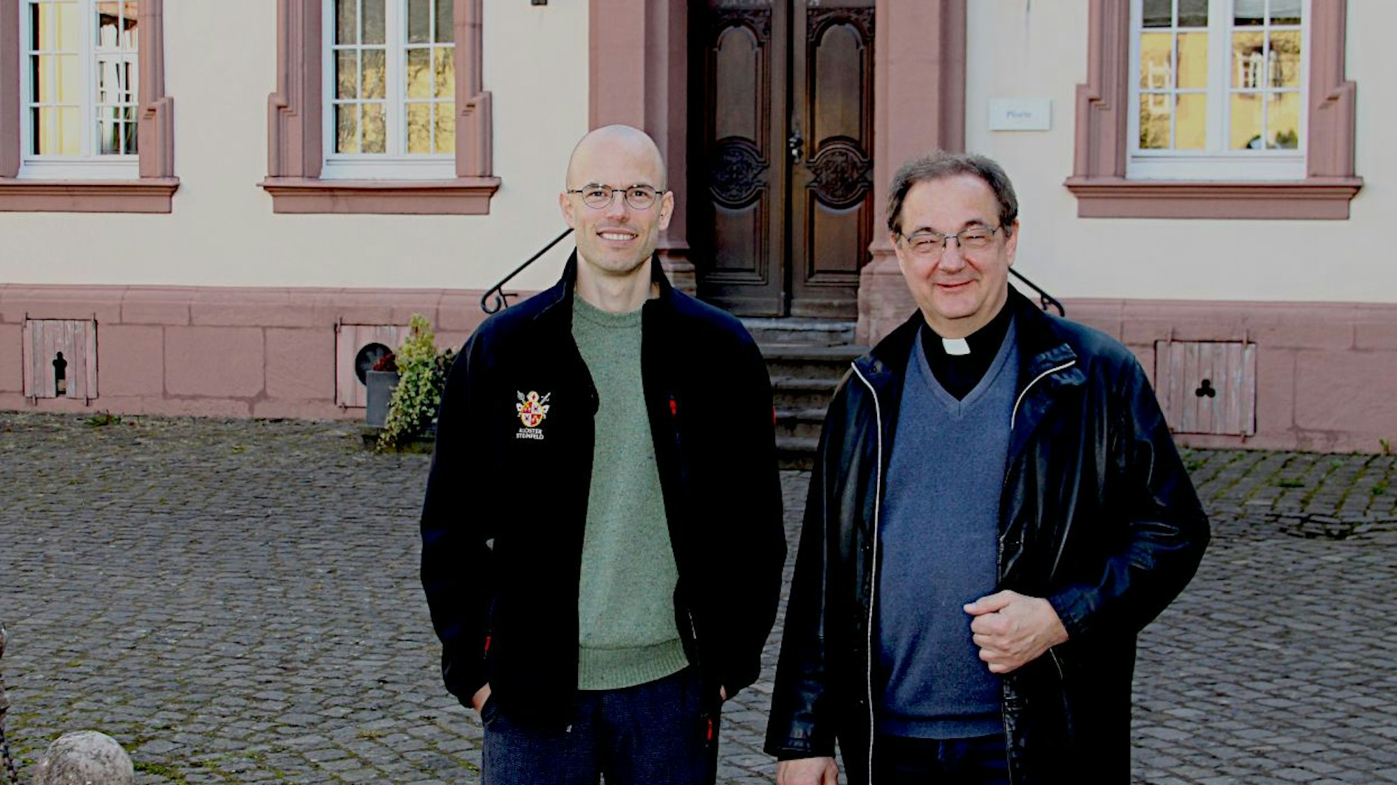 Zwei Männer stehen vor einem der Klostergebäude.