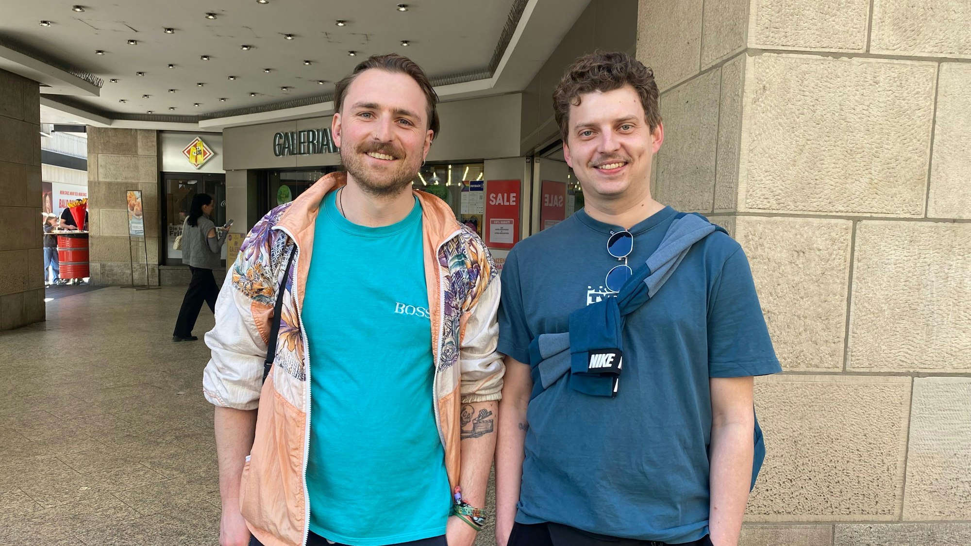 Zwei Männer in bunten Shirts schauen in die Kamera.