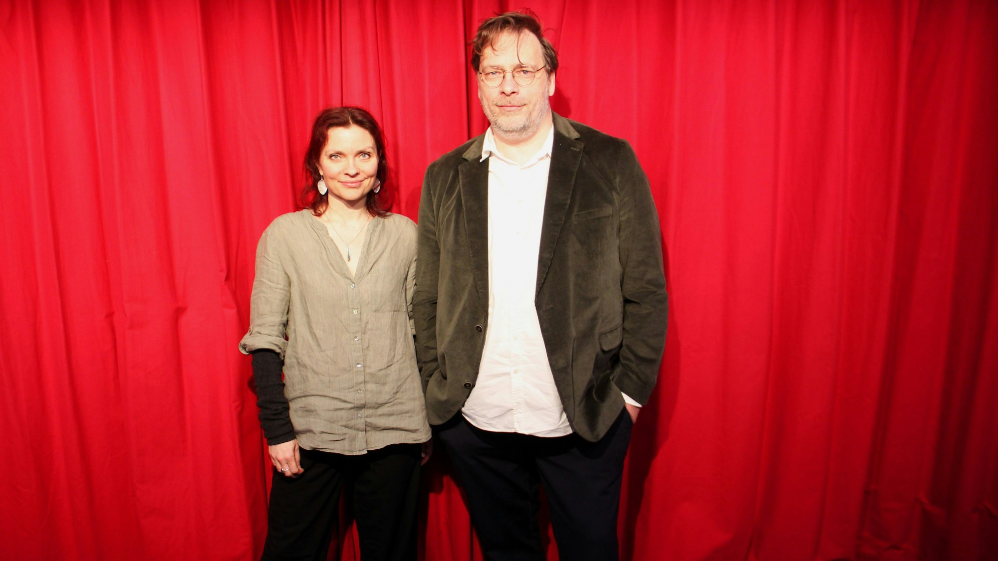 Eine Frau und ein Mann stehen vor einem roten Vorhang.