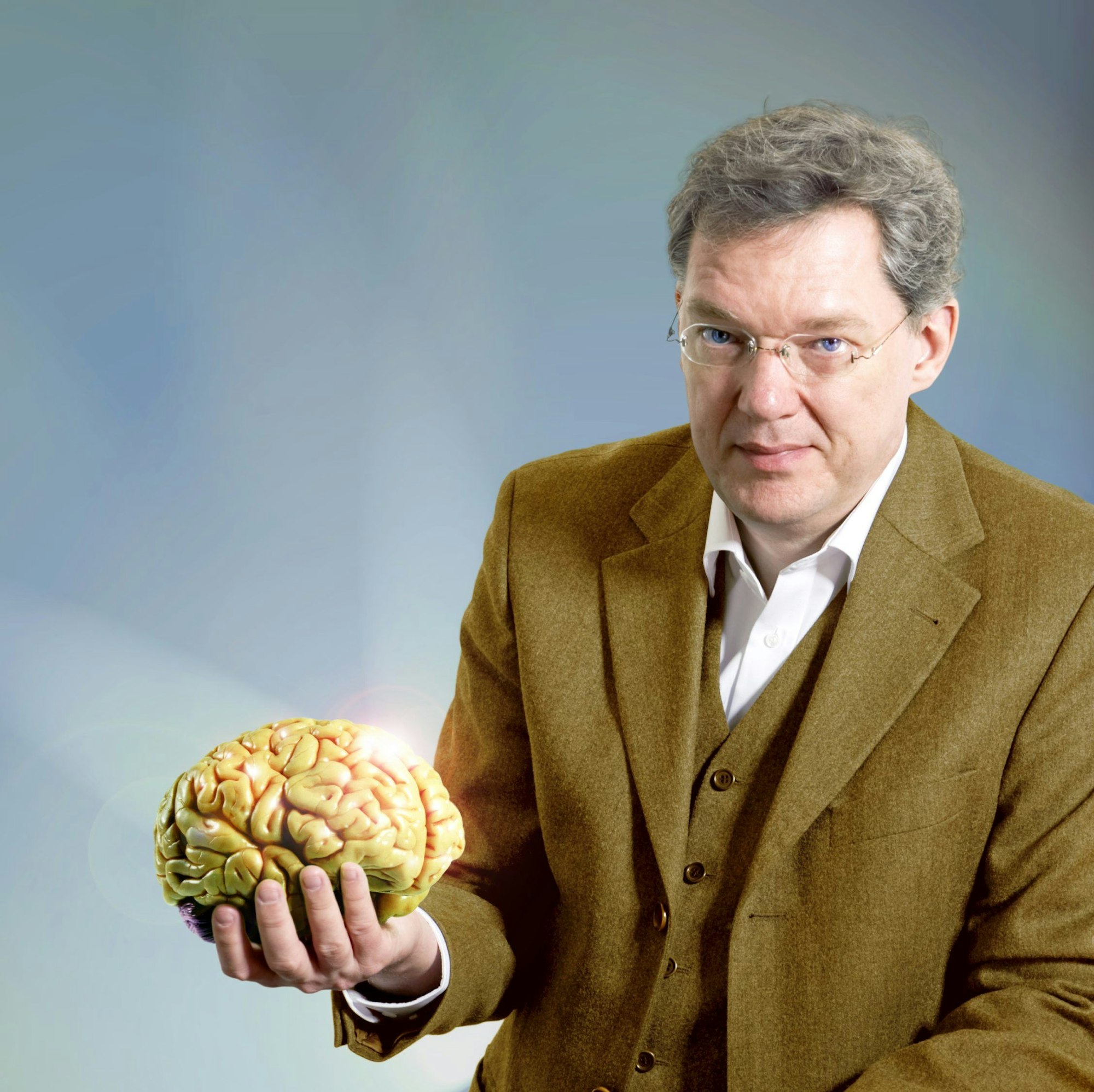 Der Neurologe Dr. Magnus Heier präsentiert in seiner rechten Hand ein Gehirn.