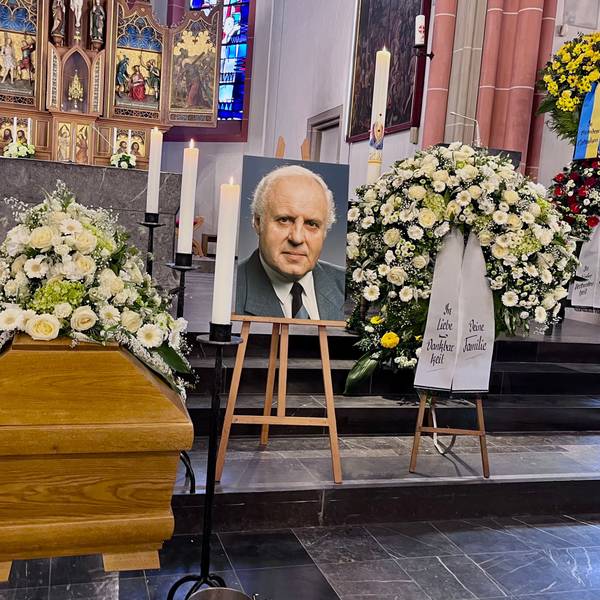 Vor dem Altar sind der Sarg, ein Foto des Verstorbenen und Blumenschmuck zu sehen.