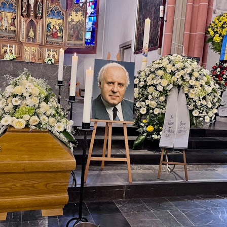 Vor dem Altar sind der Sarg, ein Foto des Verstorbenen und Blumenschmuck zu sehen.