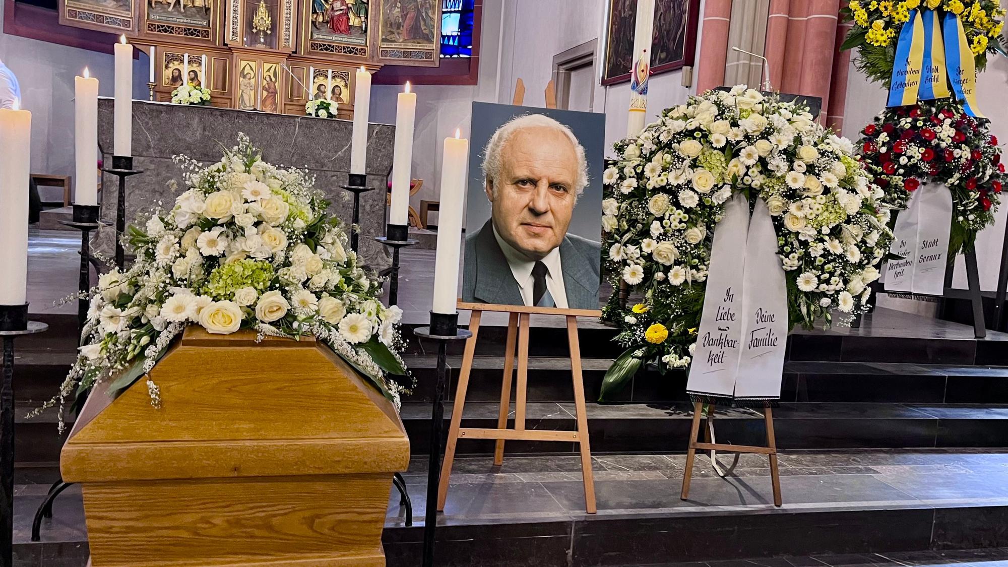 Vor dem Altar sind der Sarg, ein Foto des Verstorbenen und Blumenschmuck zu sehen.