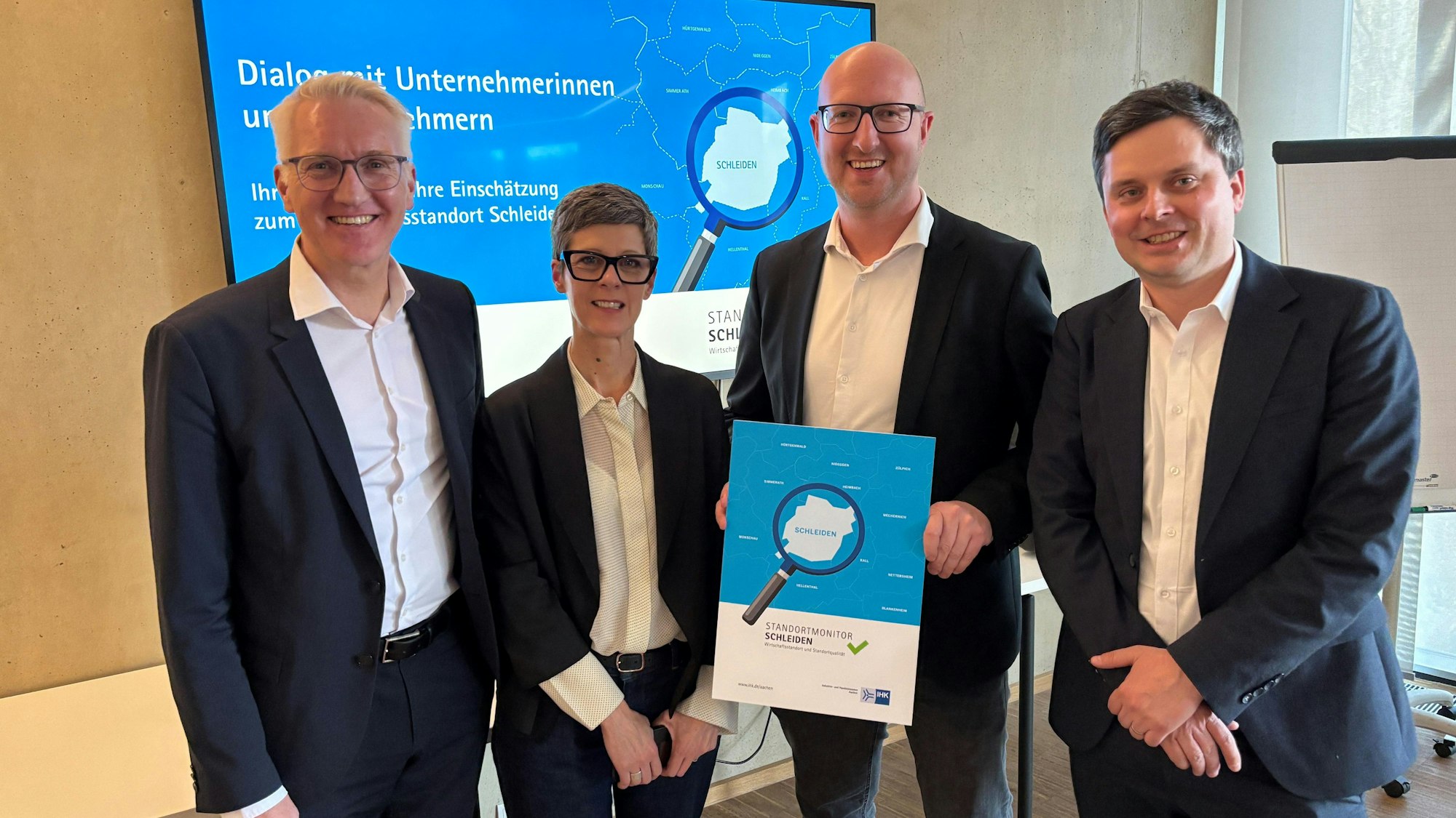 Drei Männer und eine Frau stehen nebeneinander und präsentieren das Heft mit der Untersuchung.