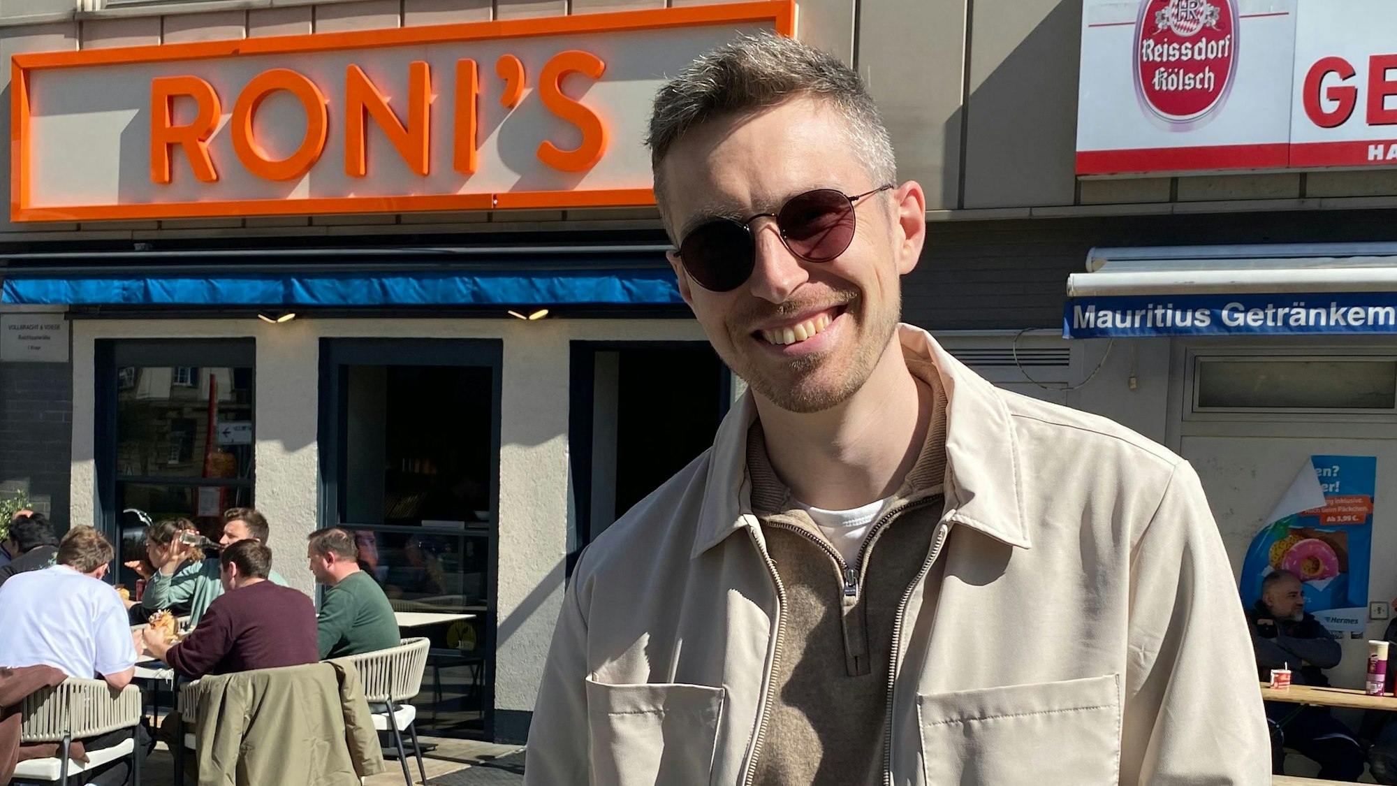 Ein Mann mit Sonnenbrille lächelt in die Kamera.