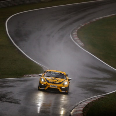 Das Foto zeigt einen Rennwagen auf regenasser Straße auf dem Nürburgring.