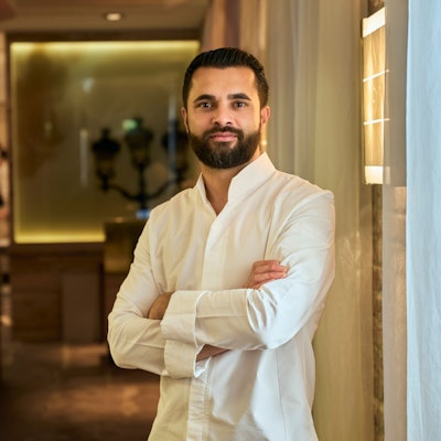 Portrait von Dennis Kuckuck, er steht mit verschränkten Armen in seinem Restaurant.