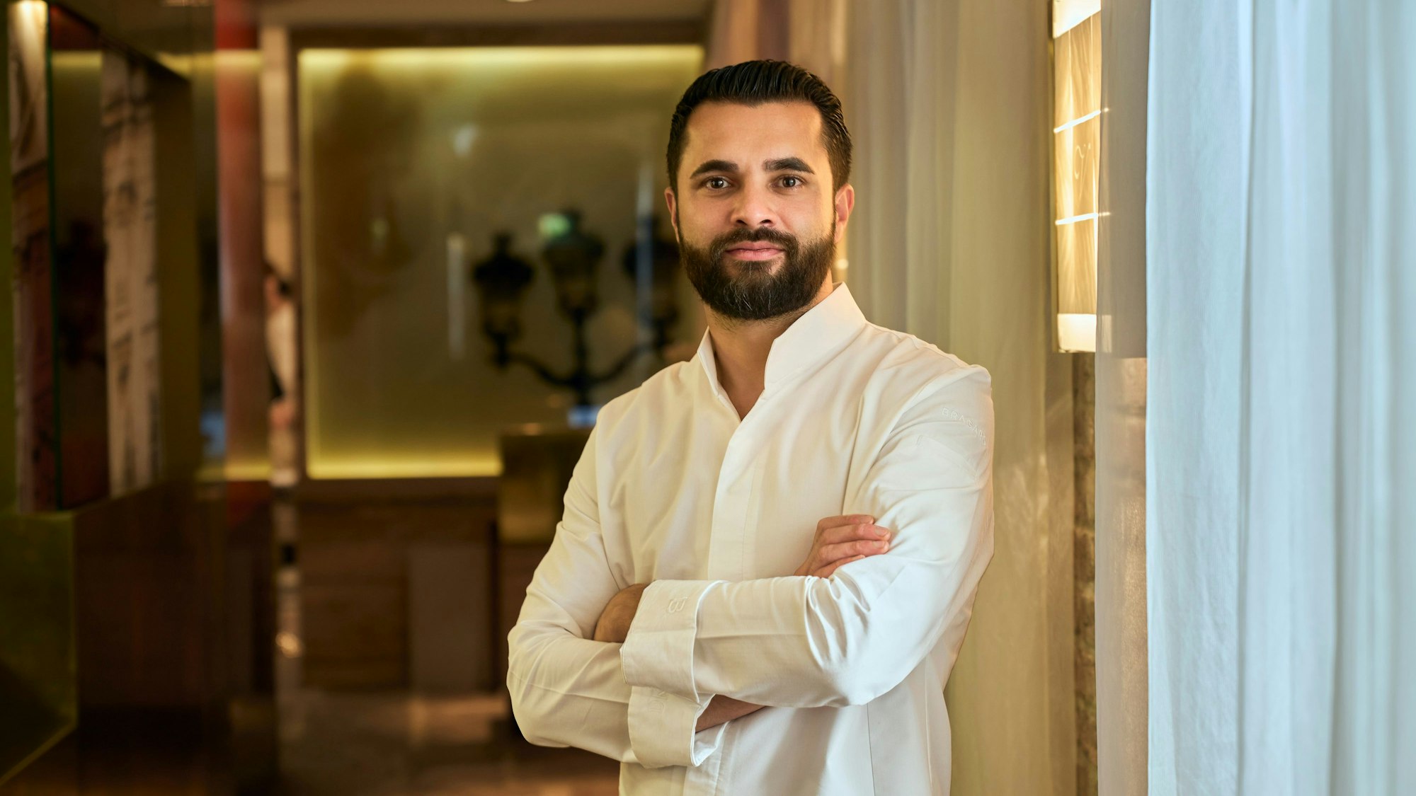 Portrait von Dennis Kuckuck, er steht mit verschränkten Armen in seinem Restaurant.