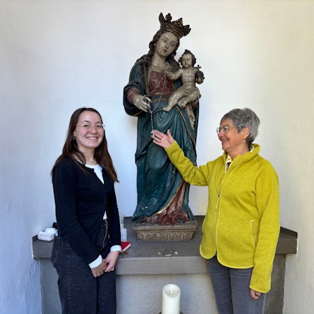 Die Obengenannten flankieren eine barocke Marien-Figur mit Jesus-Kind. und lächeln Dr. Andrea Korte-Böger gestikuliert mit einer Hand und schaut in Richtung von Johanna Baldus.