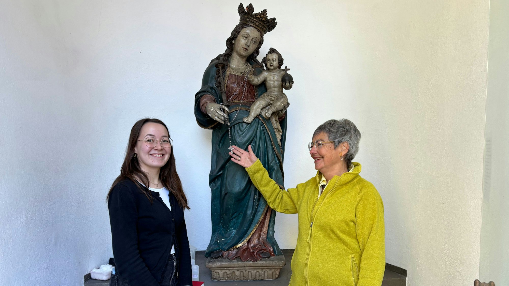 Die Obengenannten flankieren eine barocke Marien-Figur mit Jesus-Kind. und lächeln Dr. Andrea Korte-Böger gestikuliert mit einer Hand und schaut in Richtung von Johanna Baldus.