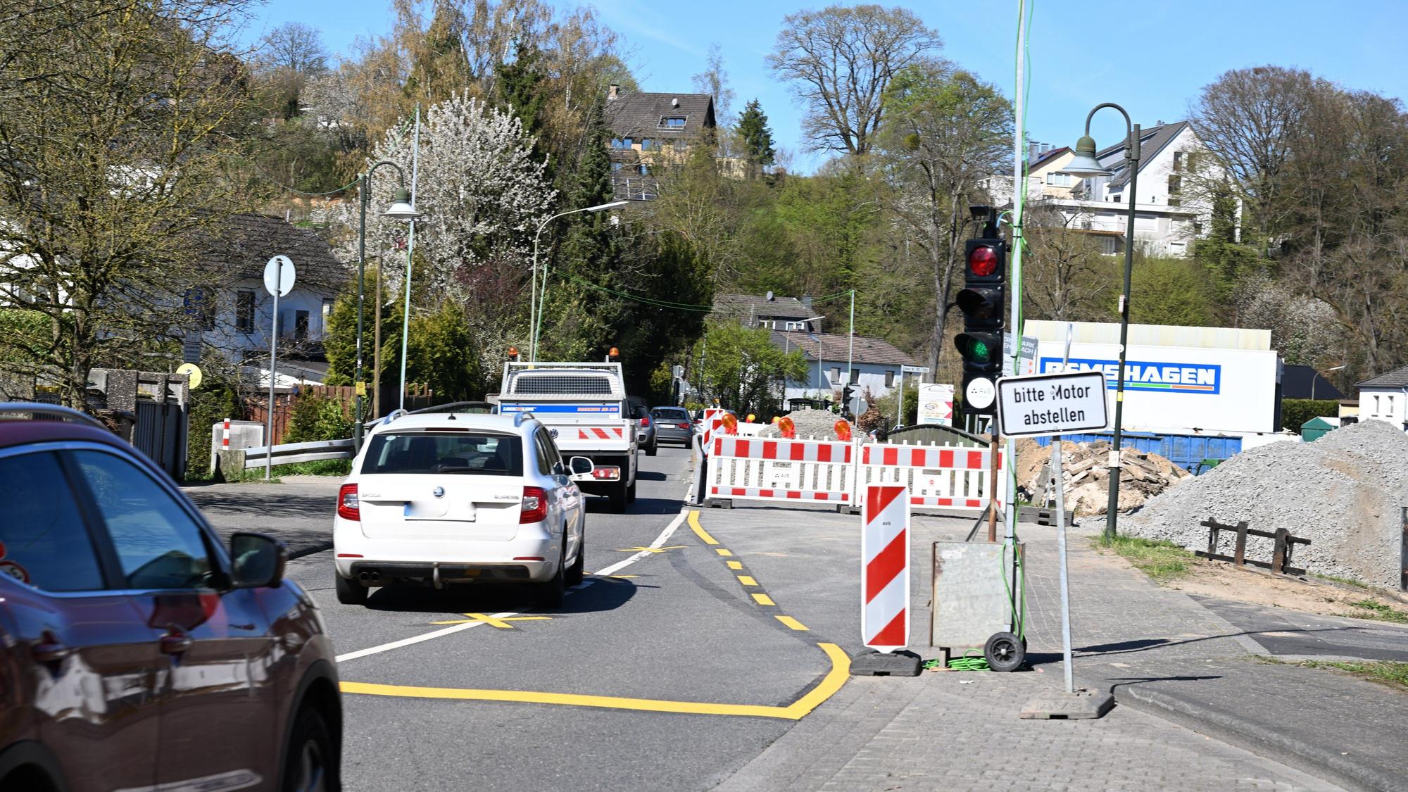 Eine Baustellenampel, dahinter eine Bake, fünf Autos fahren hintereinander auf einer einspurigen Straße