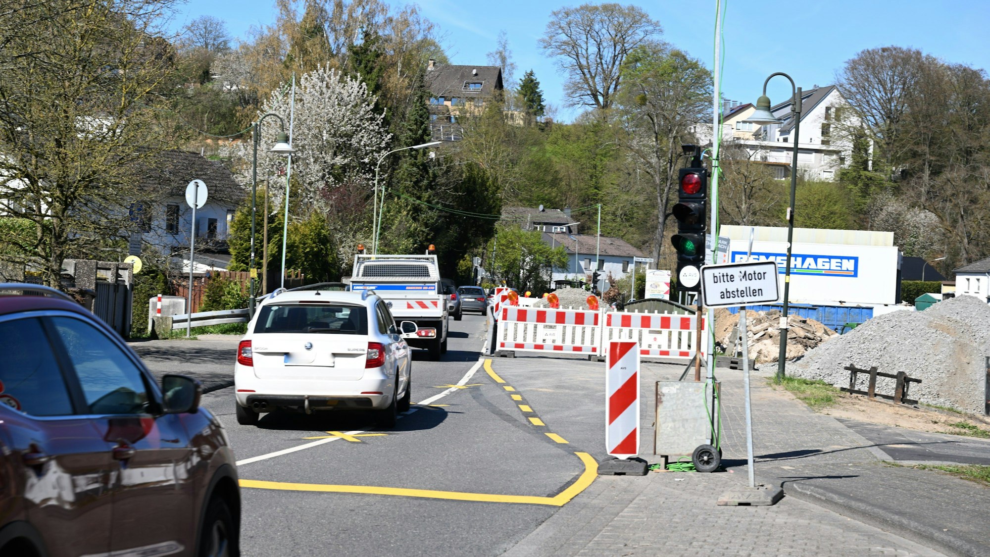 Eine Baustellenampel, dahinter eine Bake, fünf Autos fahren hintereinander auf einer einspurigen Straße