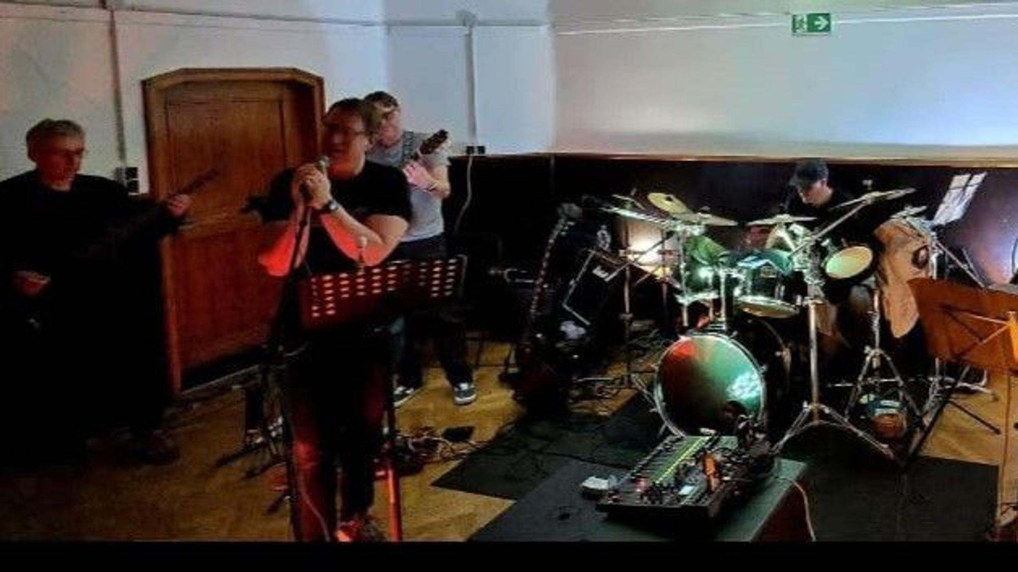 Eine Band spielt Schlagzeug, Bass und Gitarre.